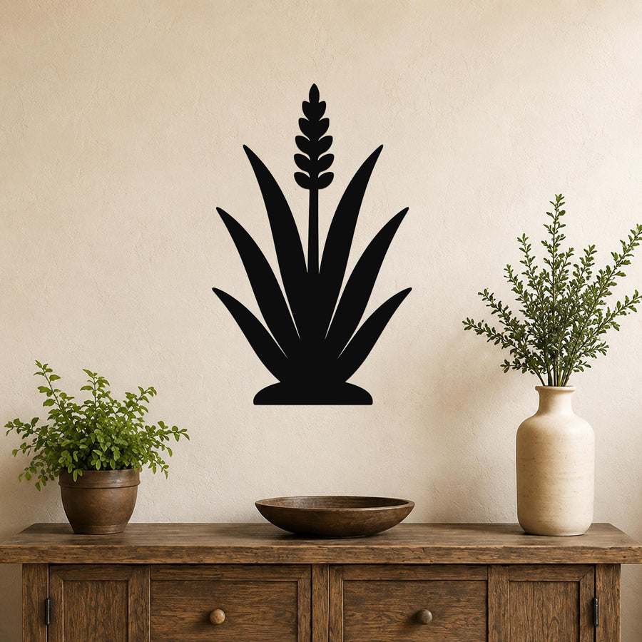 Black metal agave wall art with a central flower spike cutout, mounted on a beige wall above a wooden console table with potted plants.