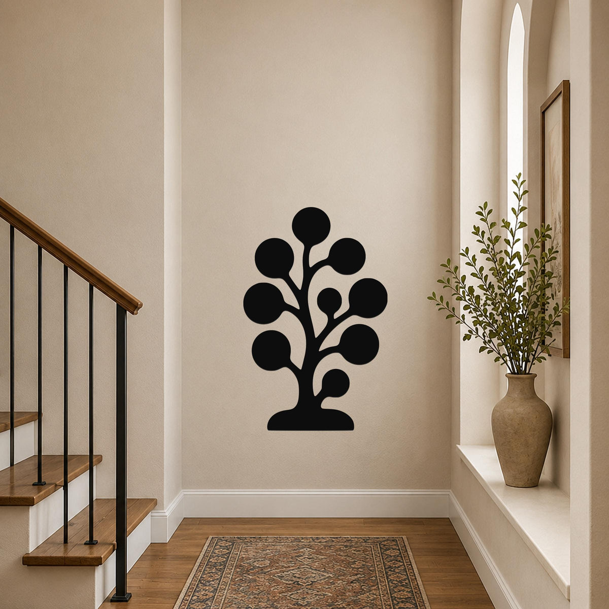 Black metal wall art in a stylized tree silhouette with circular leaf shapes, mounted on a hallway wall above a patterned rug near a staircase.