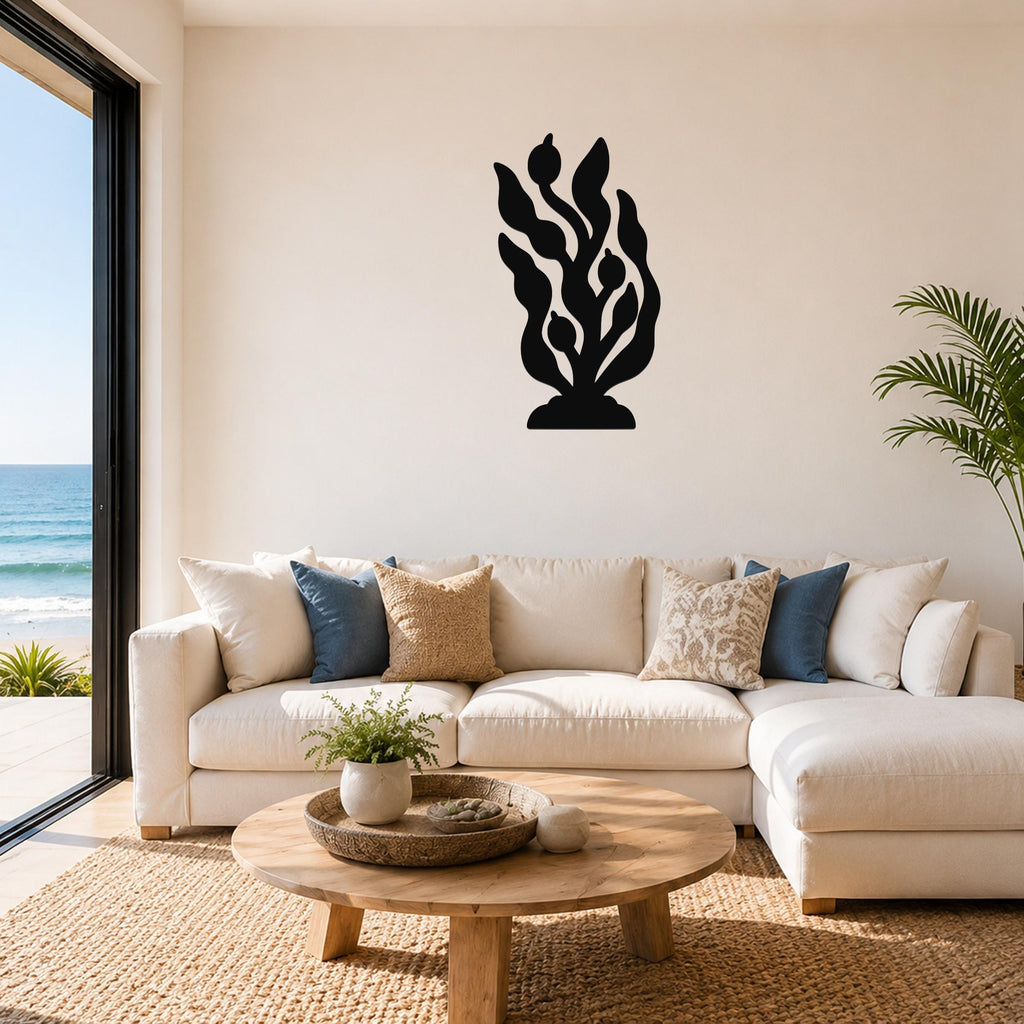 Black metal kelp and seaweed wall art with flowing leaf and bulb cutouts, mounted on a living room wall above a white sofa.