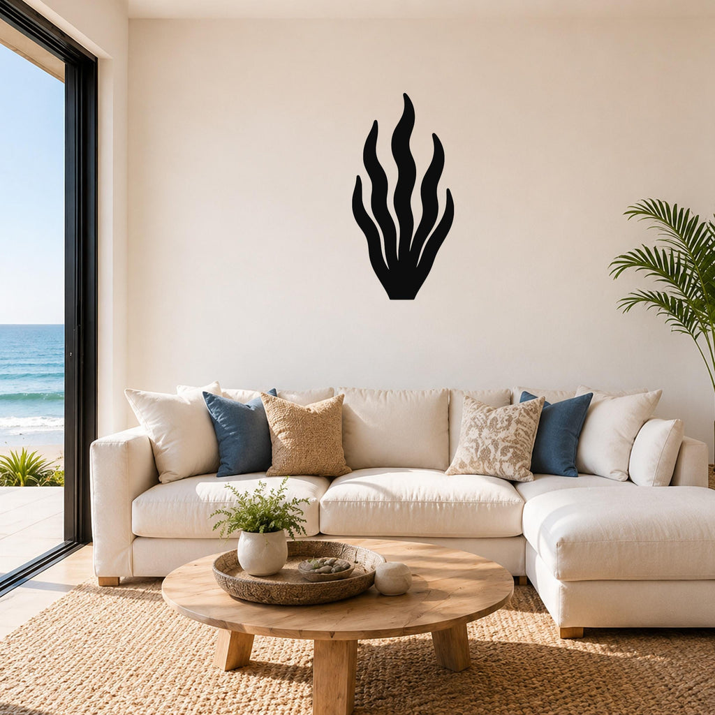 Black metal kelp wall art with flowing frond cutouts, mounted above a white sofa in a coastal living room.