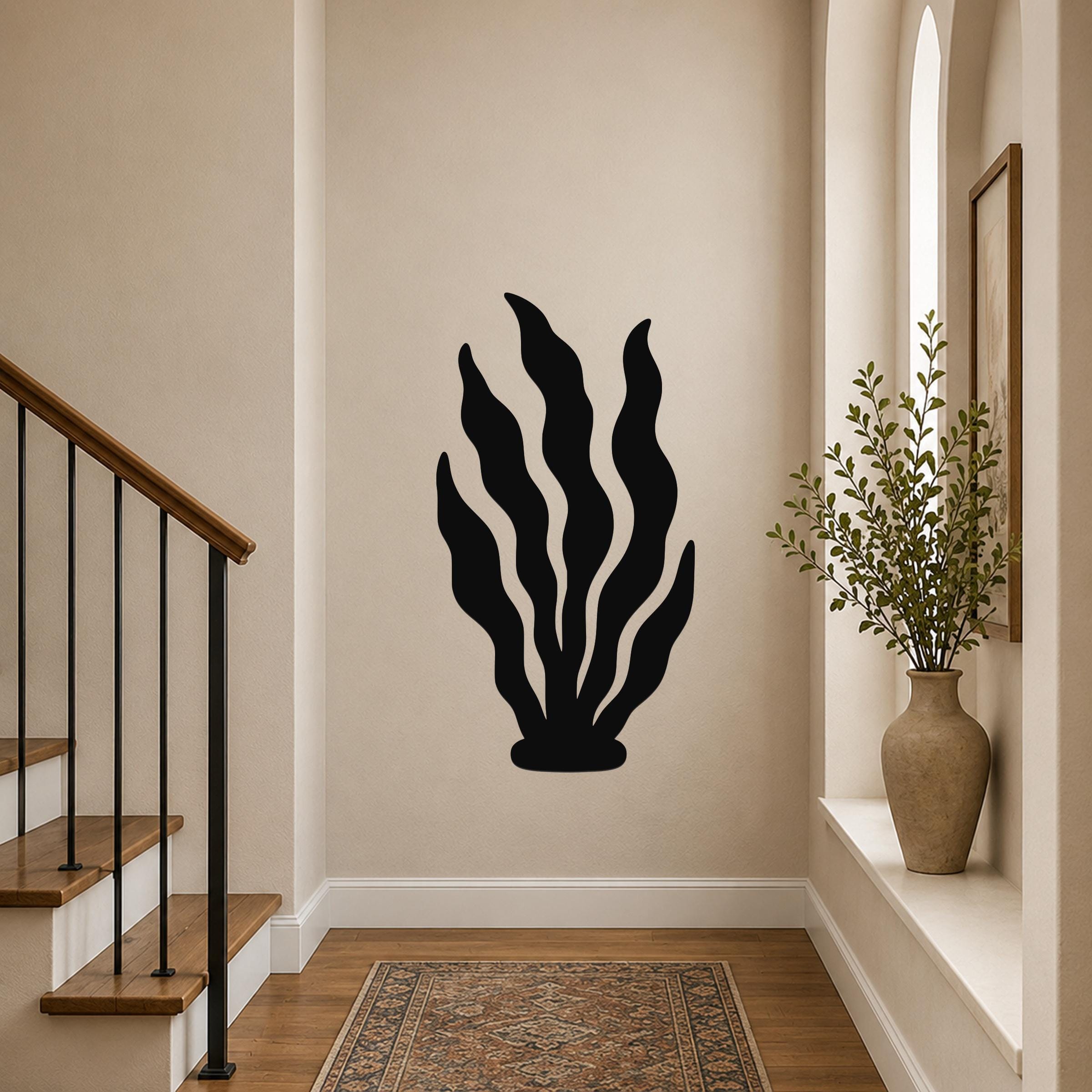Black metal wall art in a kelp silhouette design, mounted on a hallway wall above a patterned rug near a staircase.