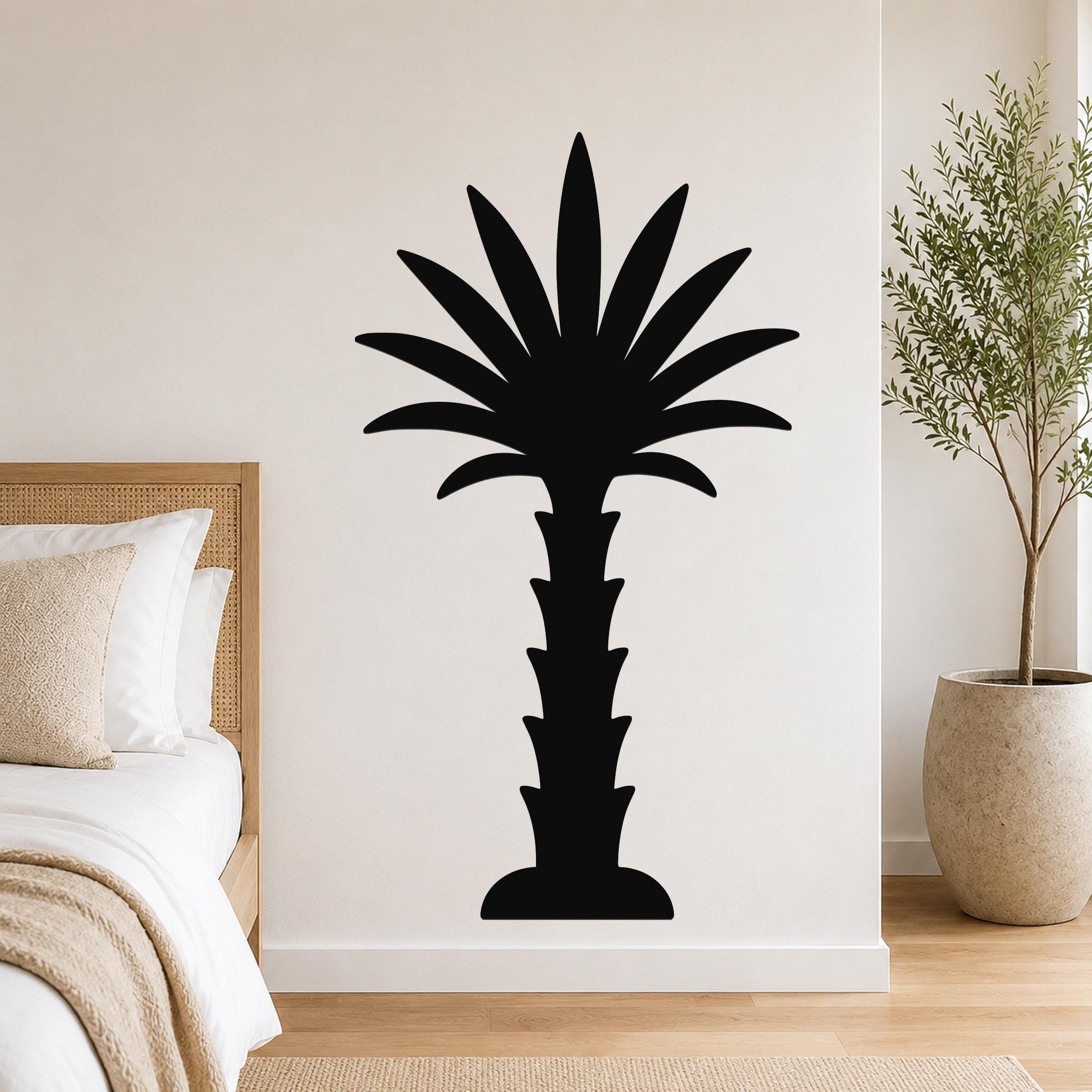 Black metal palm tree wall art silhouette mounted on a bedroom wall above a bed, with a potted plant nearby.