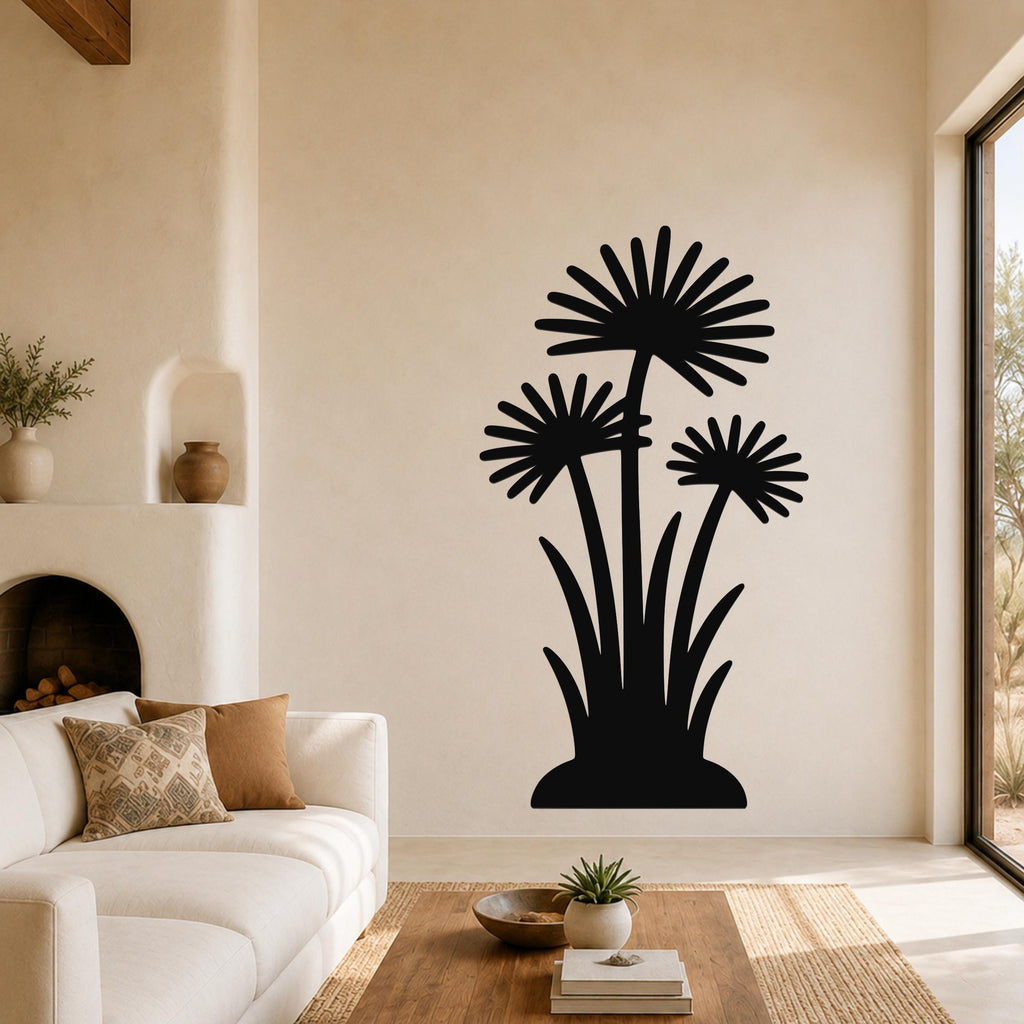 Black metal wall art with a silhouette of three wildflowers and long leaves, mounted on a living room wall above a sofa.