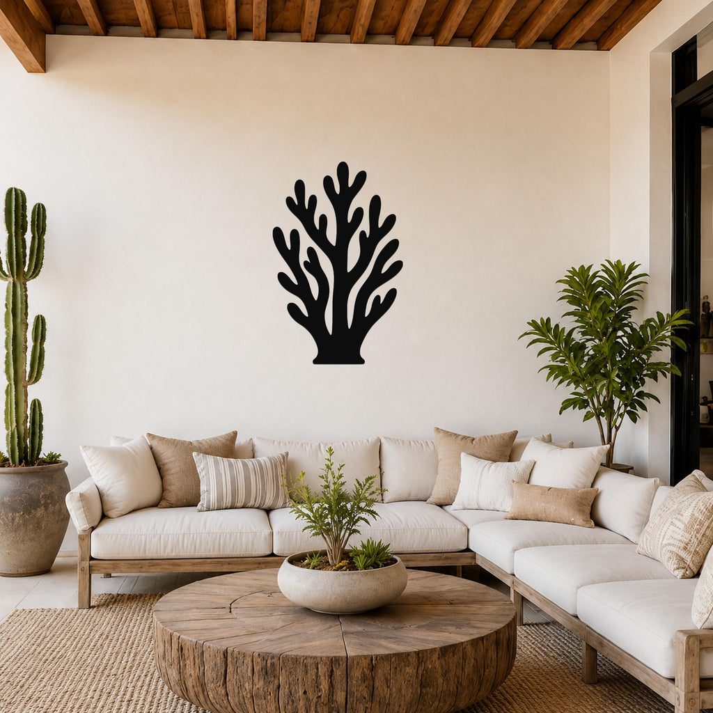 Black metal coral wall art with branching cutouts, mounted on a white wall above a white sofa in a living room.