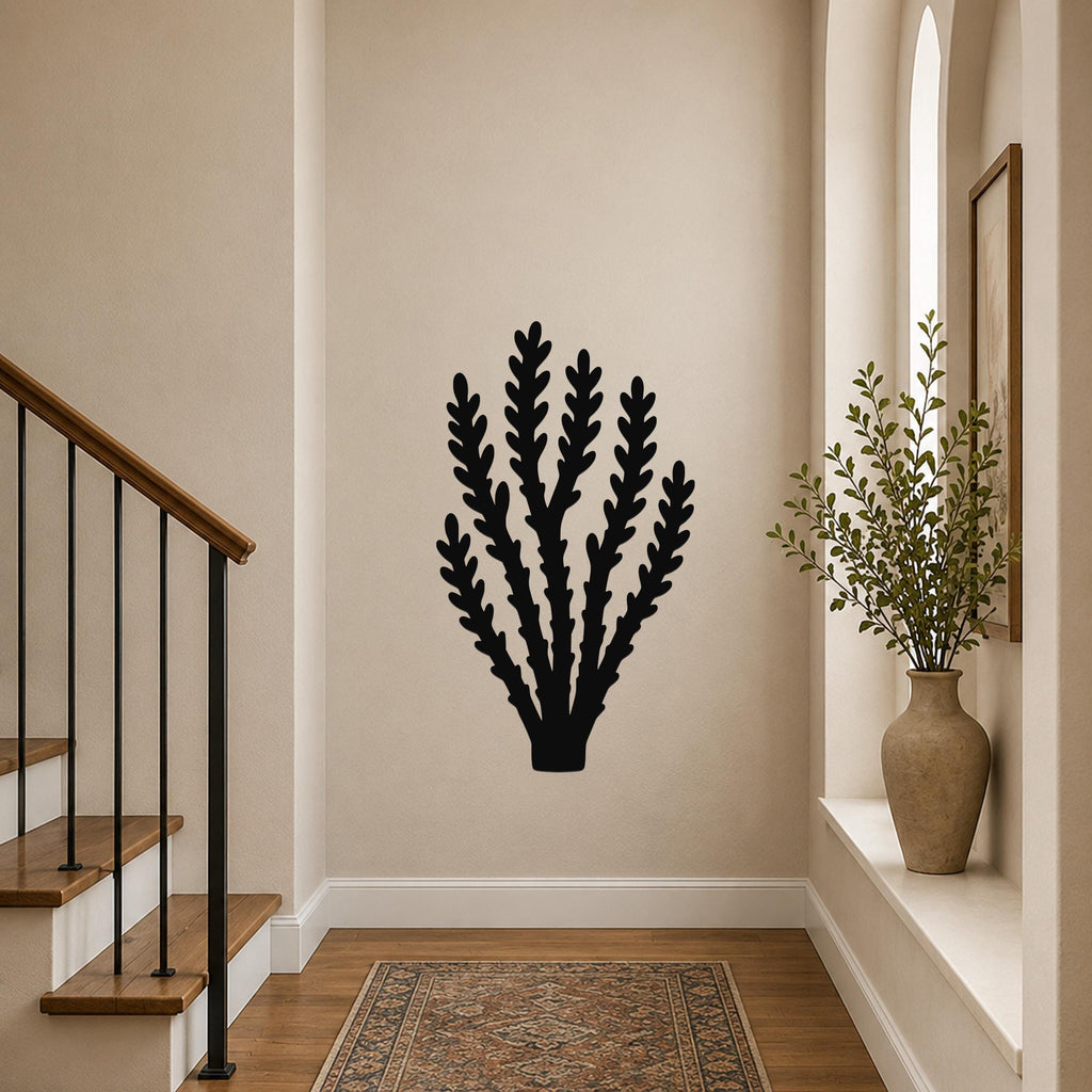 Black metal wall art in a branching plant silhouette, mounted on a hallway wall above a patterned rug near a staircase.