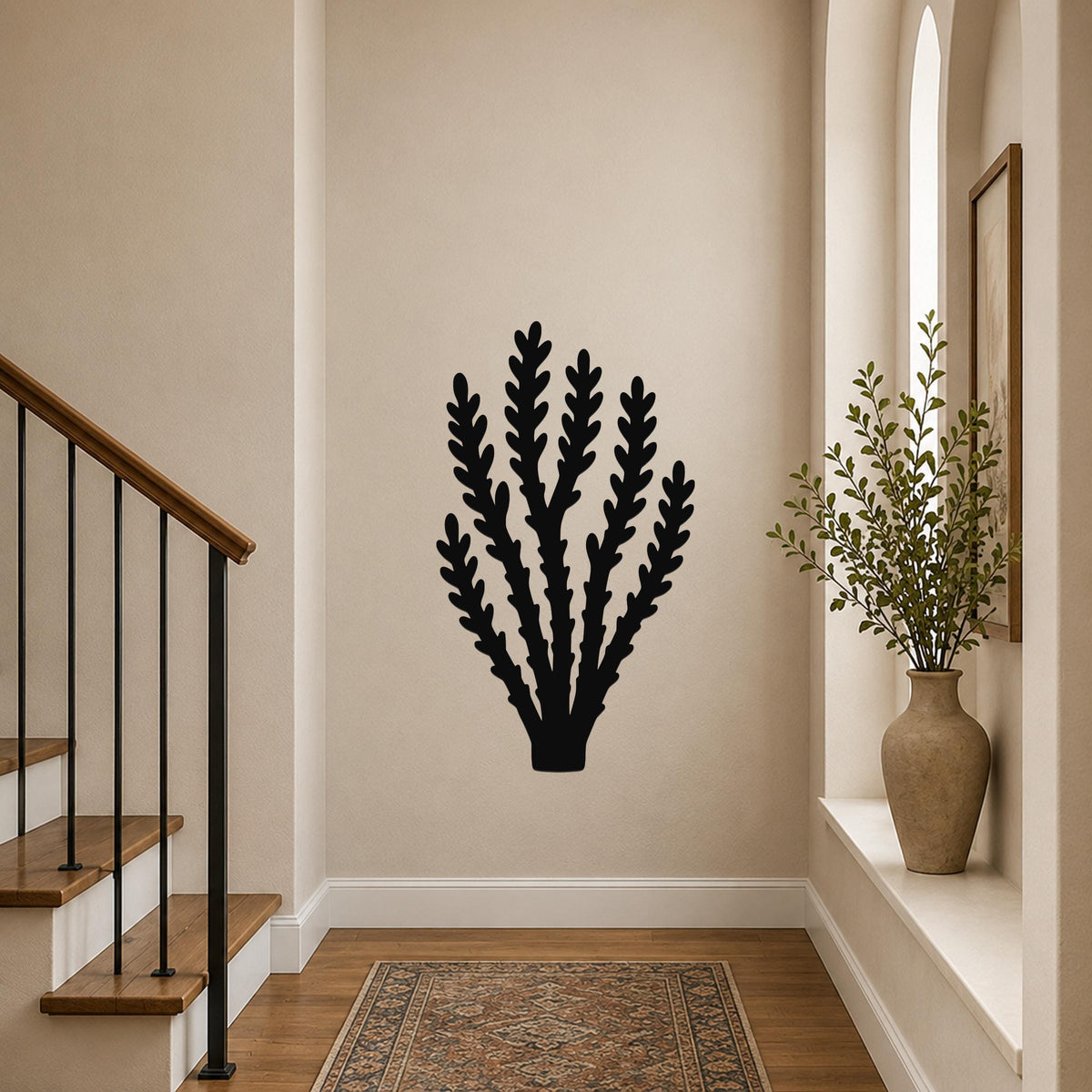Black metal wall art in a branching plant silhouette, mounted on a hallway wall above a patterned rug near a staircase.