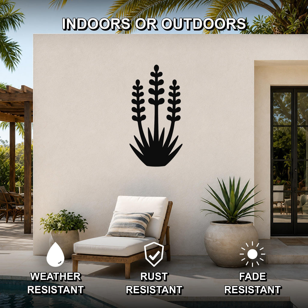 Black metal yucca wall art with layered leaf cutouts, mounted on an outdoor patio wall above a lounge chair.