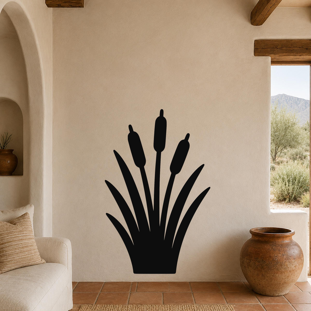 Black metal cattail wall art silhouette with three seed heads and long leaves, mounted on a beige living room wall above a sofa.