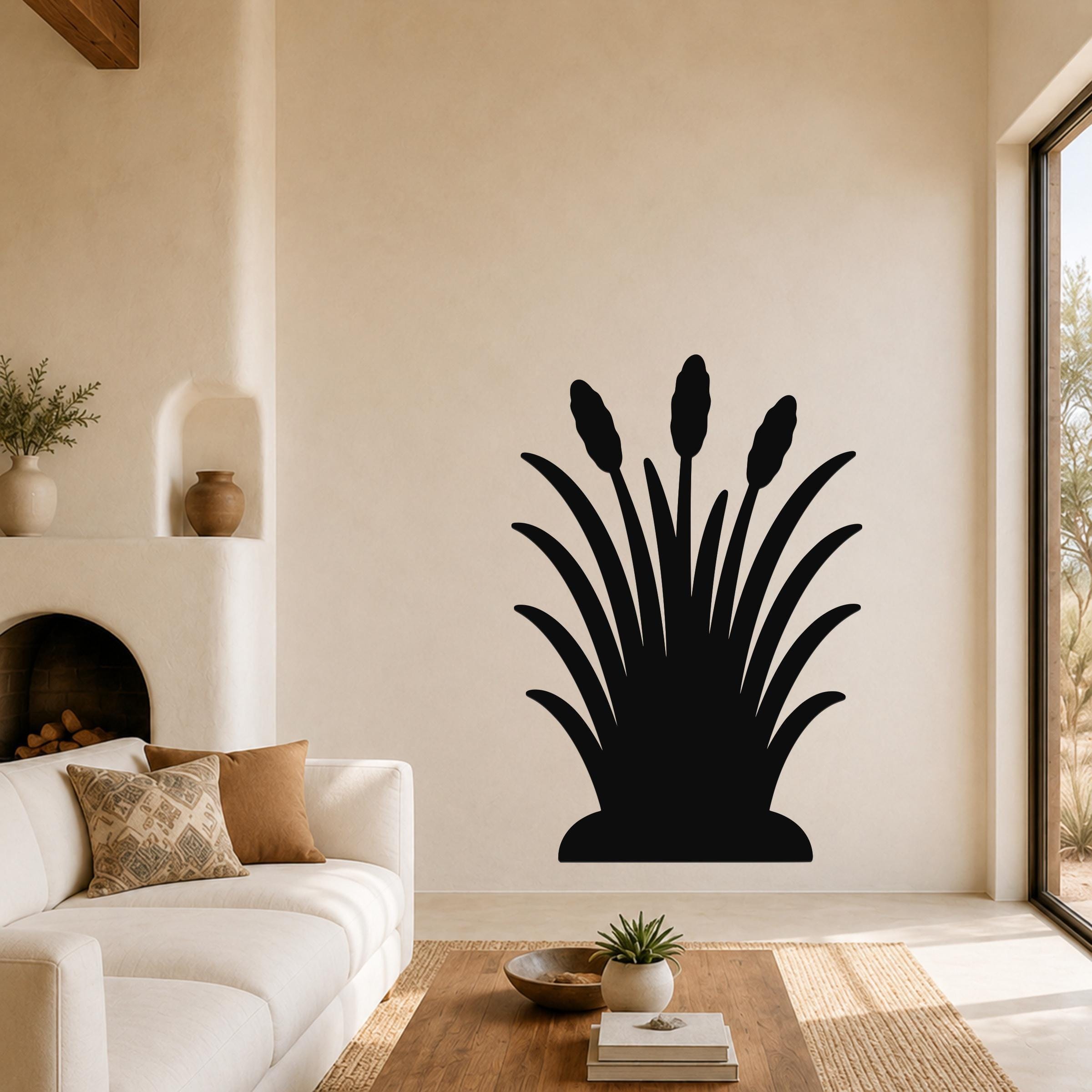 Black metal wall art in a cattail silhouette design, mounted on a living room wall above a sofa.