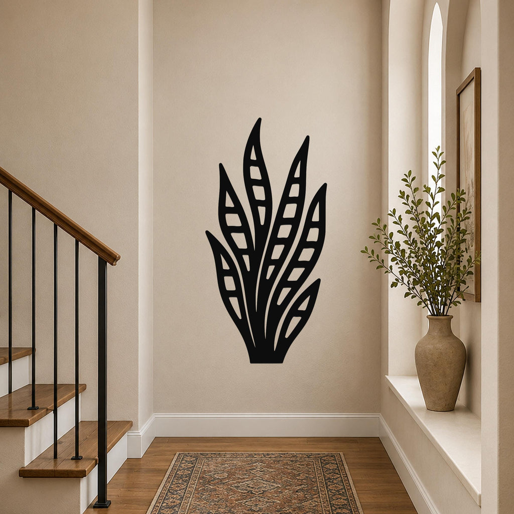 Black metal wall art in a snake plant silhouette with internal leaf cutouts, mounted on a hallway wall above a patterned rug.