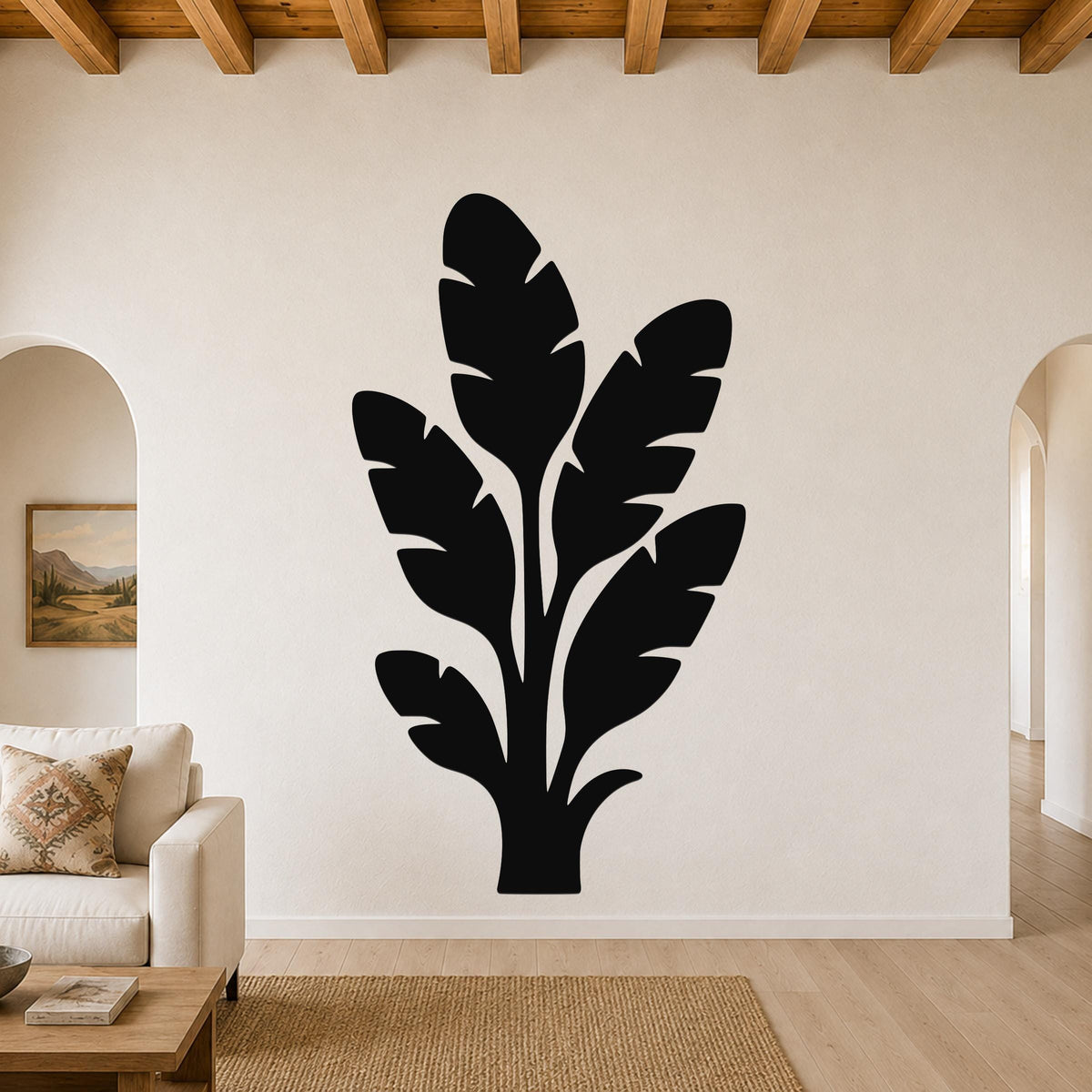 Black metal wall art featuring a tropical leaf silhouette, mounted on a living room wall above a sofa.