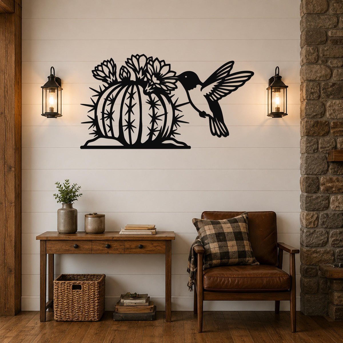 Black metal wall art featuring a hummingbird and flowering barrel cactus cutout, mounted on a white shiplap wall above a wooden console table in a living room.