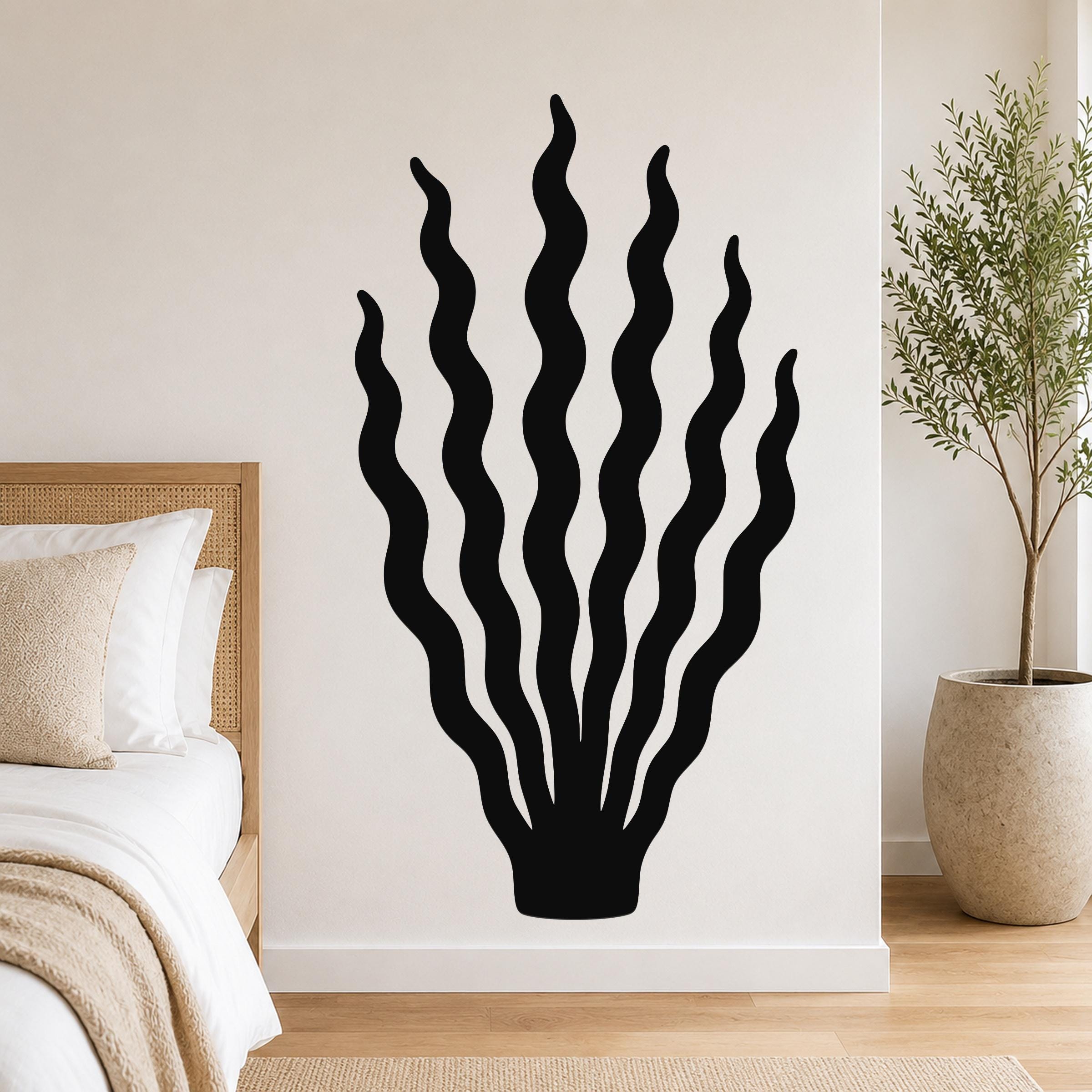 Black metal kelp wall art with wavy cutout lines, mounted on a bedroom wall above a bed.