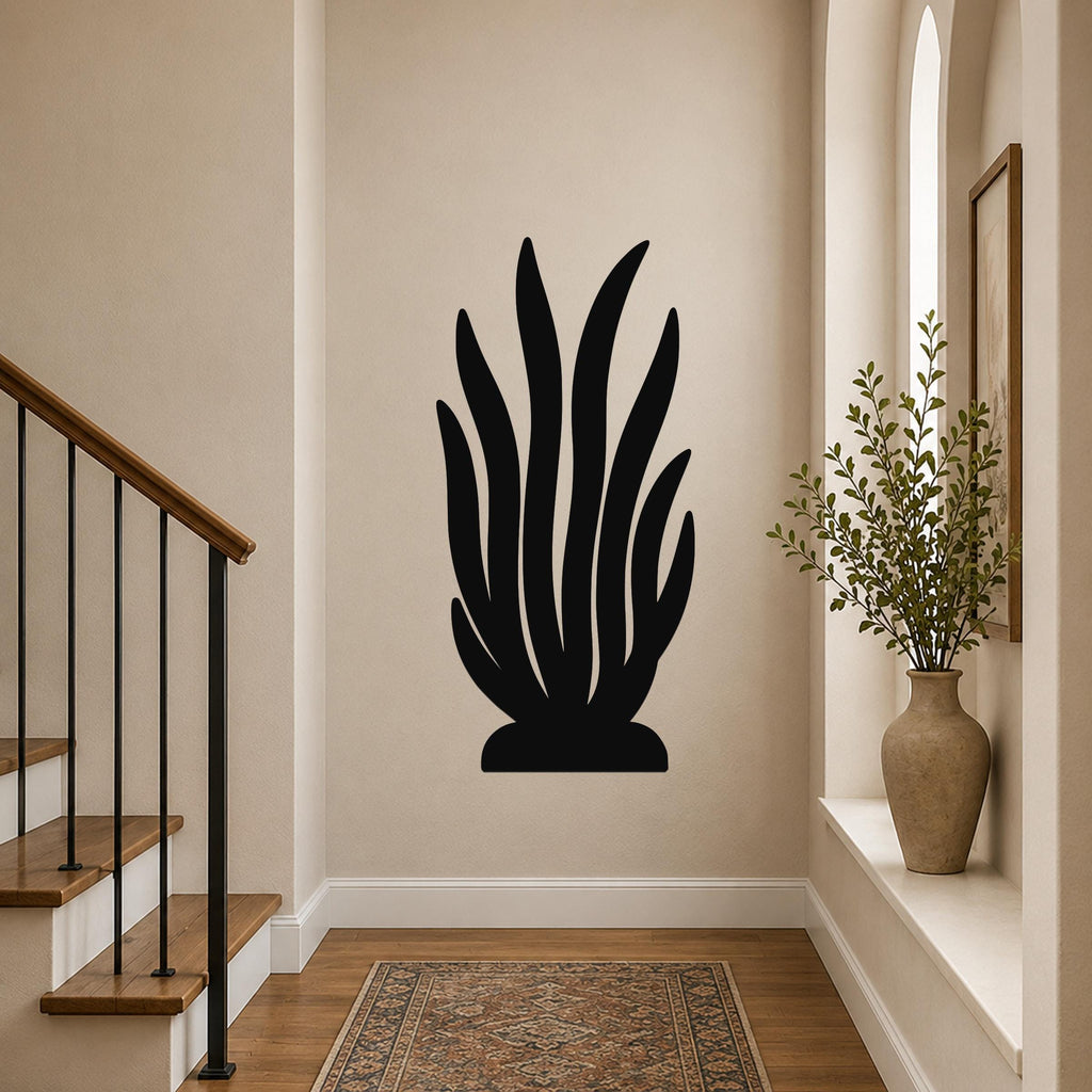 Black metal kelp wall art with leafy cutouts, mounted on a hallway wall above a patterned rug near a staircase.
