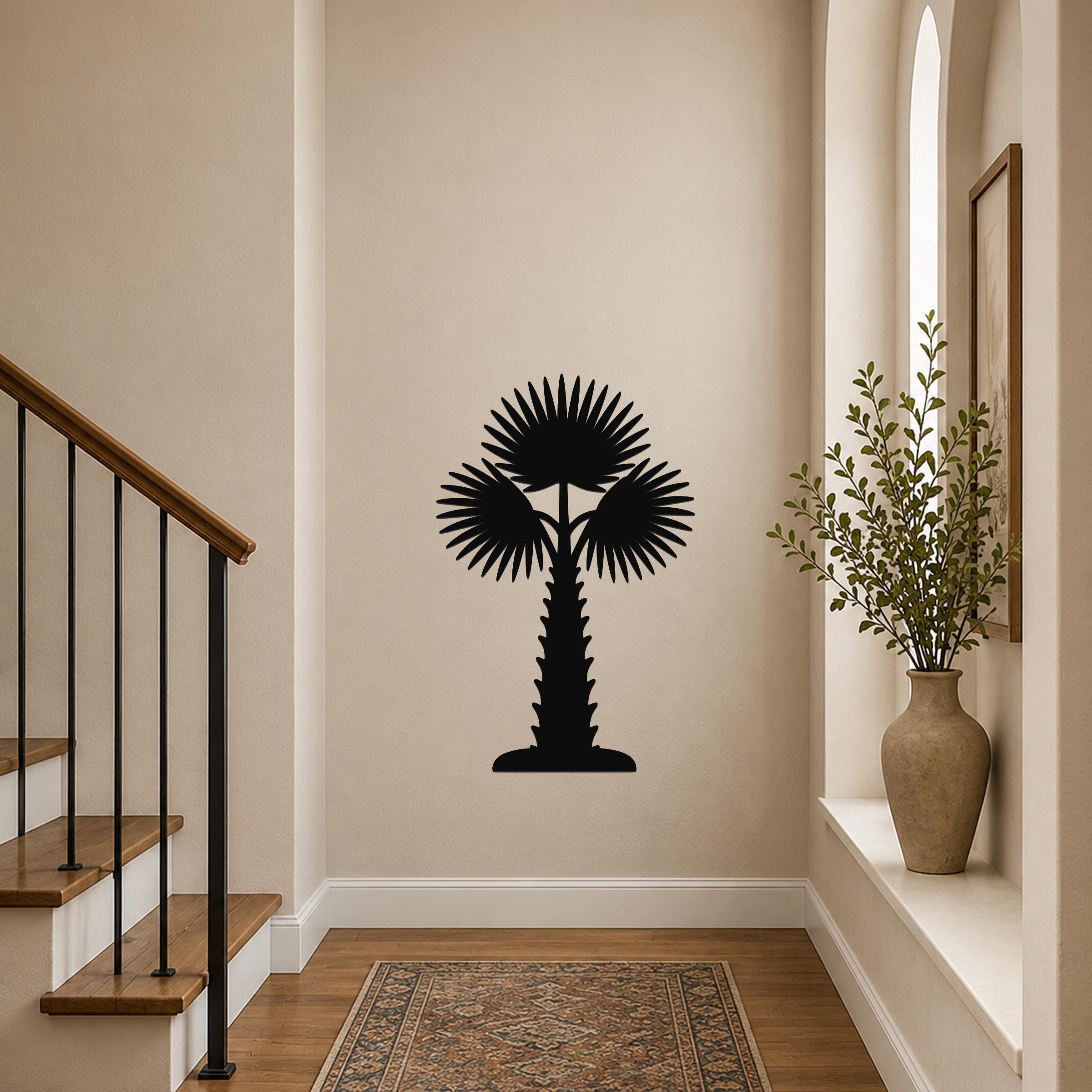 Black metal palm tree wall art with fan-shaped fronds and a textured trunk, mounted on a hallway wall above a patterned rug near a staircase.