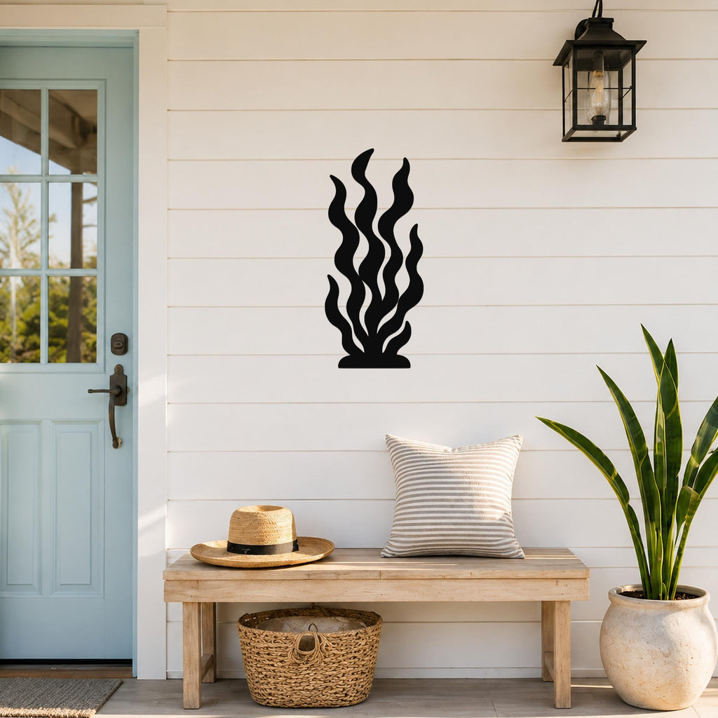 Black metal kelp wall art with wavy cutout design, mounted on a white shiplap wall above a wooden bench in a porch entryway.