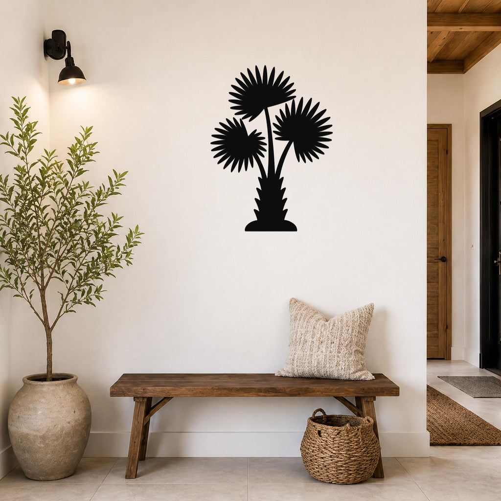 Black metal wall art silhouette of a California fan palm tree with three fronds, mounted on a white wall above a wooden bench in a modern entryway.
