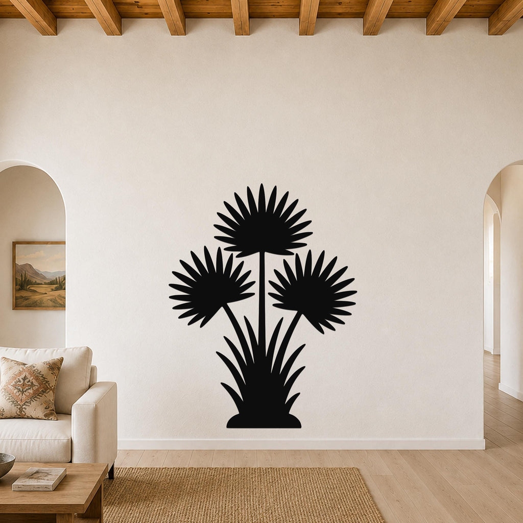 Black metal wall art silhouette of a fan palm tree with three fronds and a base of spiky leaves, mounted on a living room wall above a sofa.