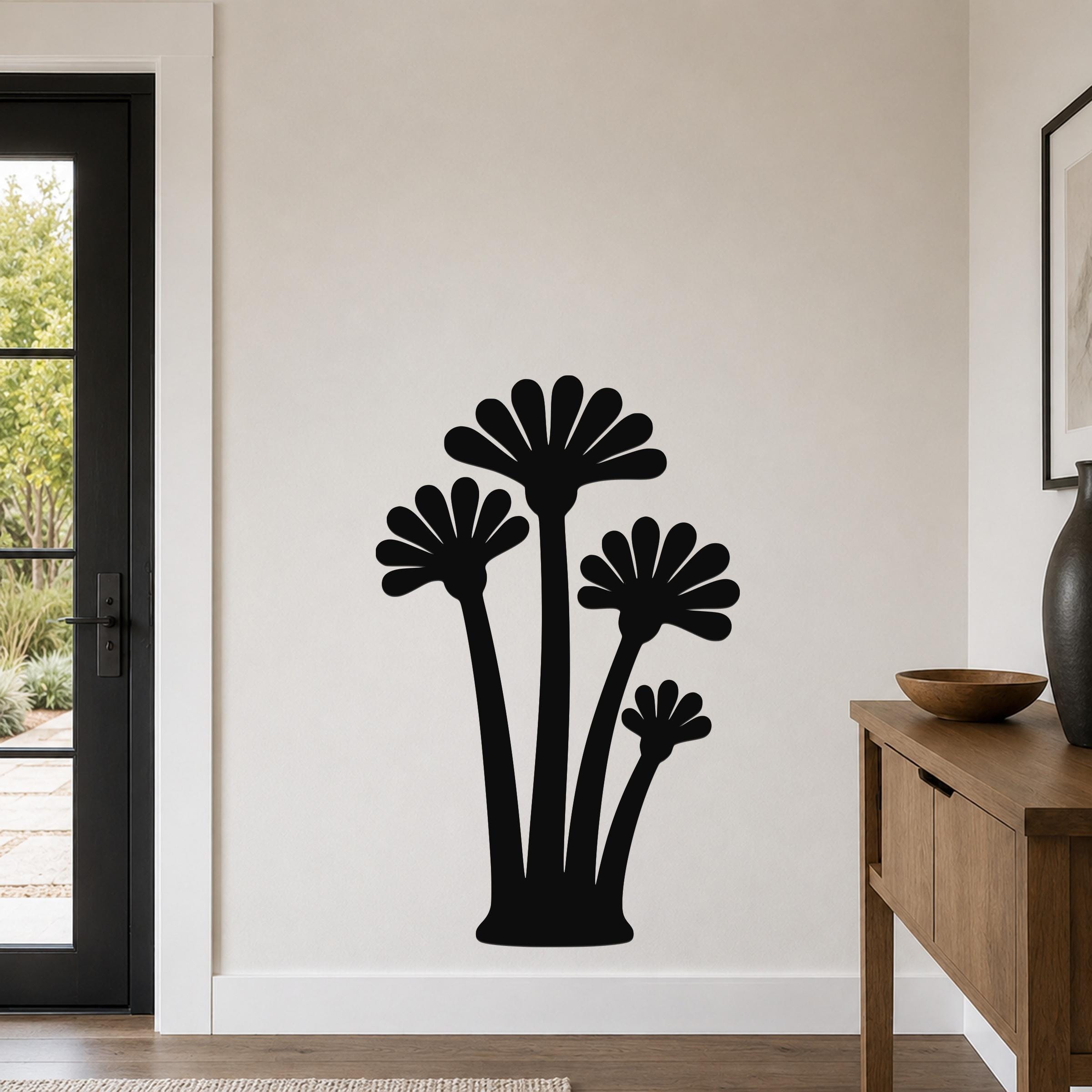 Black metal wall art featuring a silhouette of four fan-shaped palm trees, mounted on a light-colored wall in a modern entryway.