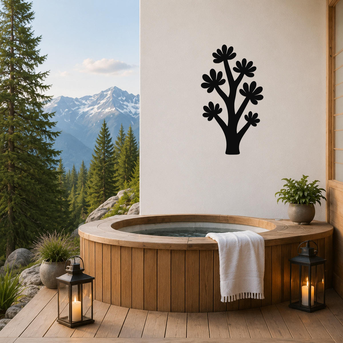 Black metal wall art in a tree silhouette with flower cutouts, mounted on a white wall above a wooden hot tub on a mountain-view deck.