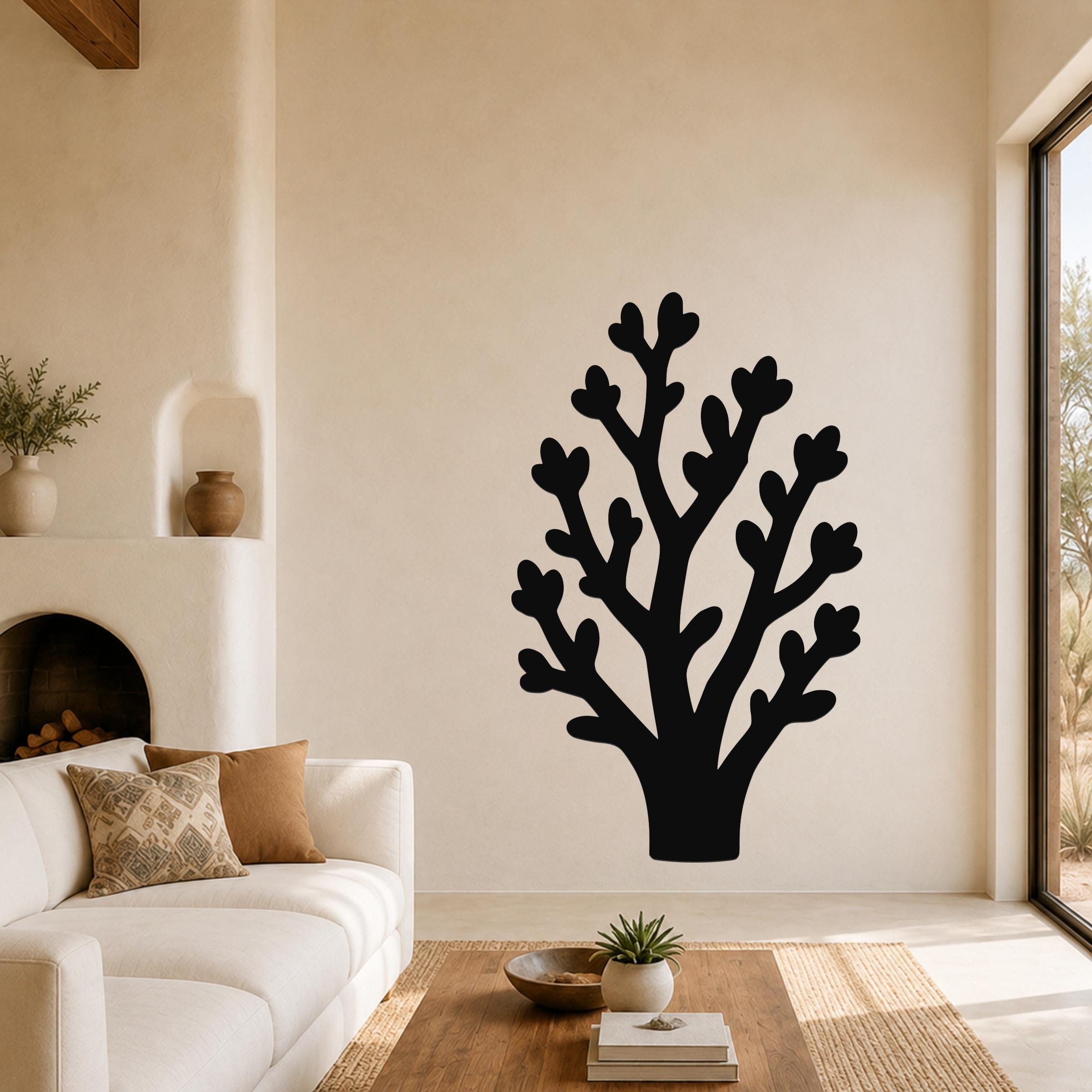Black metal wall art in a coral-like branch silhouette, mounted on a living room wall above a sofa.