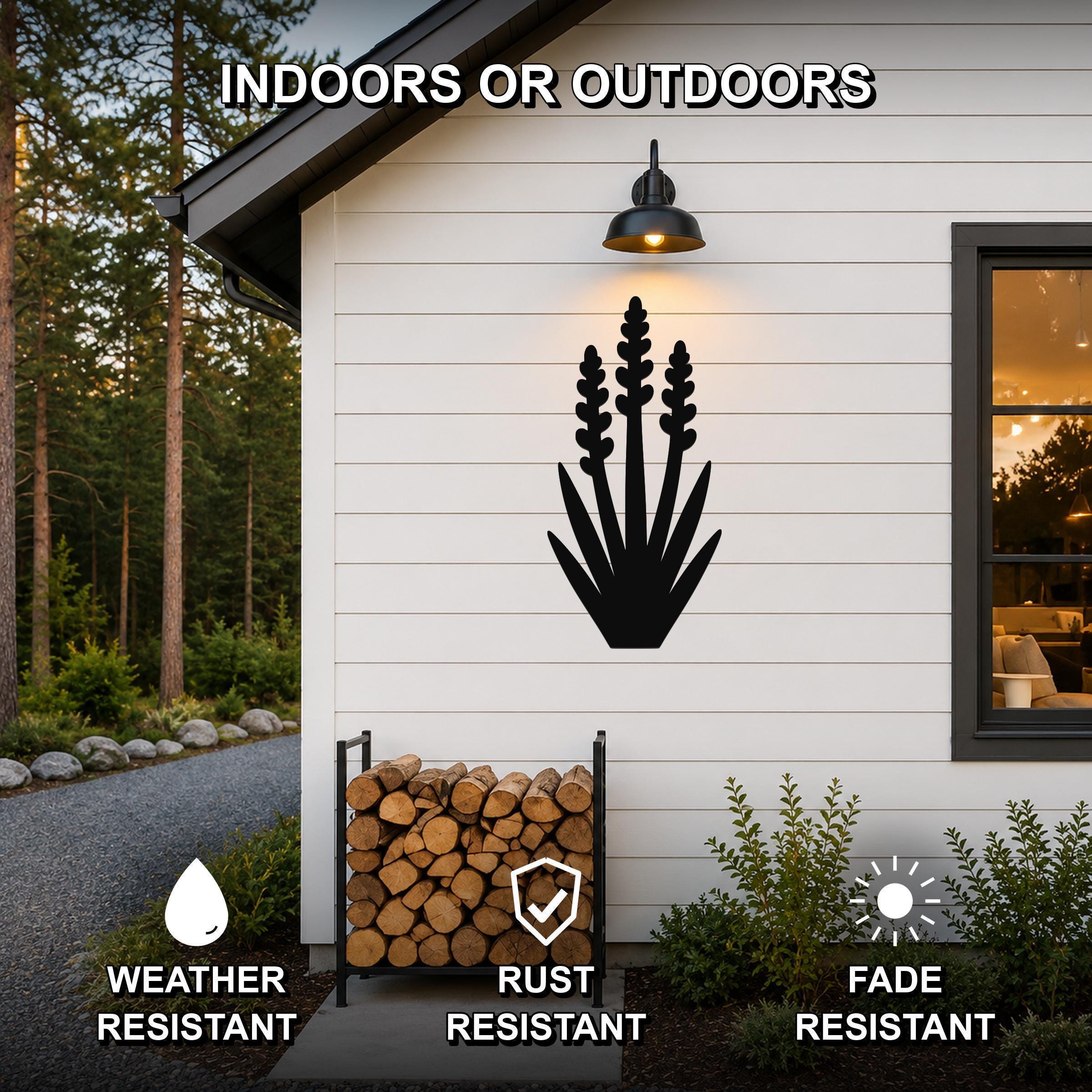 Black metal yucca wall art with layered leaf and bloom cutouts, mounted on a white exterior wall above a firewood rack, shown in an outdoor setting with weather, rust, and fade resistance features.