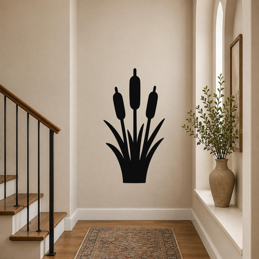 Black metal cattail wall art silhouette with three reeds and leafy base, mounted on a hallway wall above a patterned rug near a staircase.