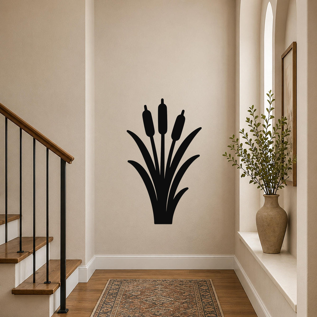 Black metal cattail wall art silhouette with three seed heads and long leaves, mounted on a hallway wall above a patterned rug near a staircase.