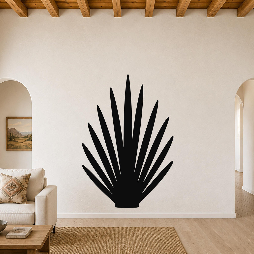 Black metal wall art in a fan-shaped silhouette of spiky grass blades, mounted on a living room wall above a beige sofa.