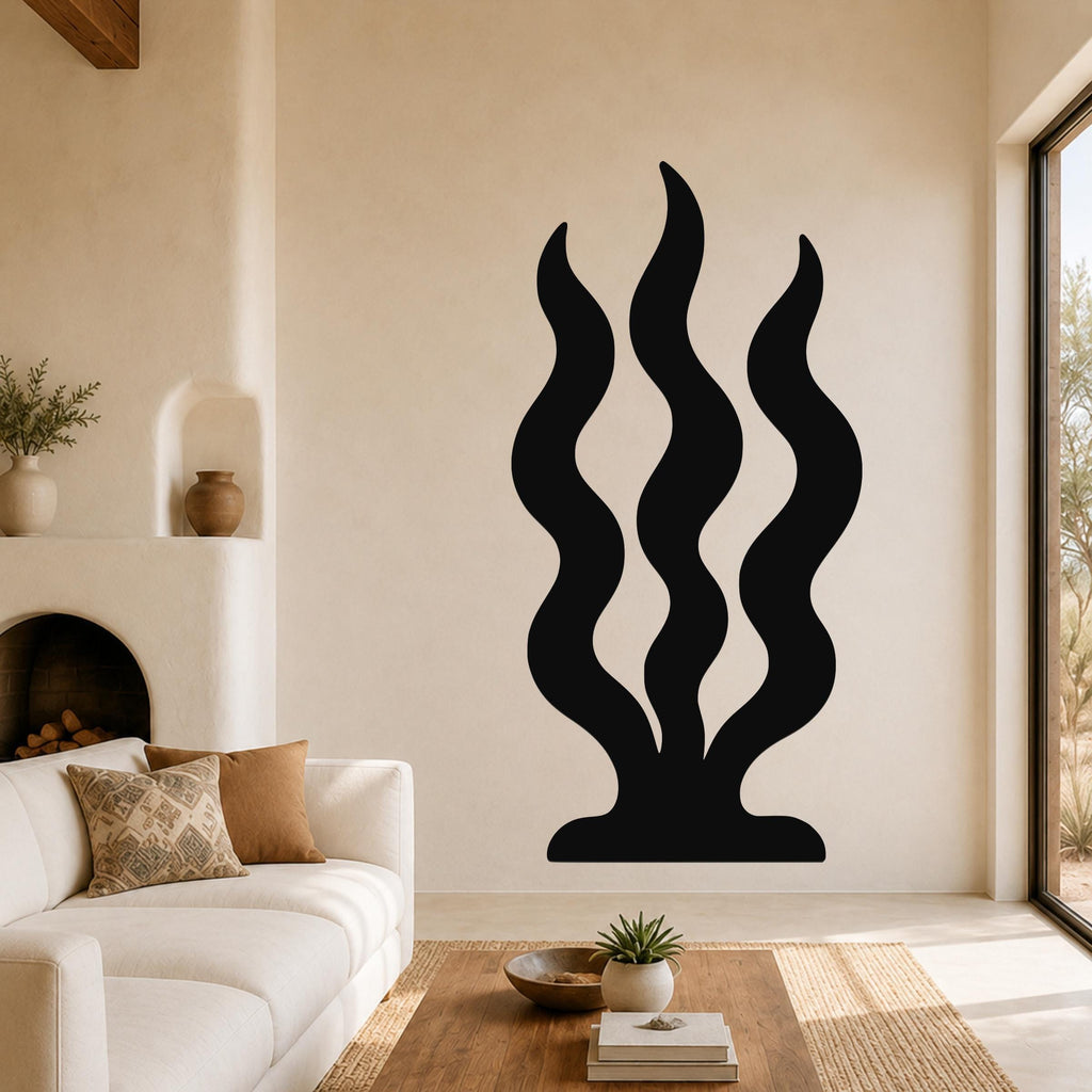 Black metal wall art with three wavy vertical cutouts resembling grass or reeds, mounted on a living room wall above a coffee table.