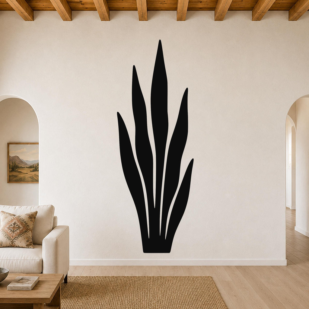 Black metal wall art in the silhouette of a snake plant, mounted on a living room wall above a sofa.