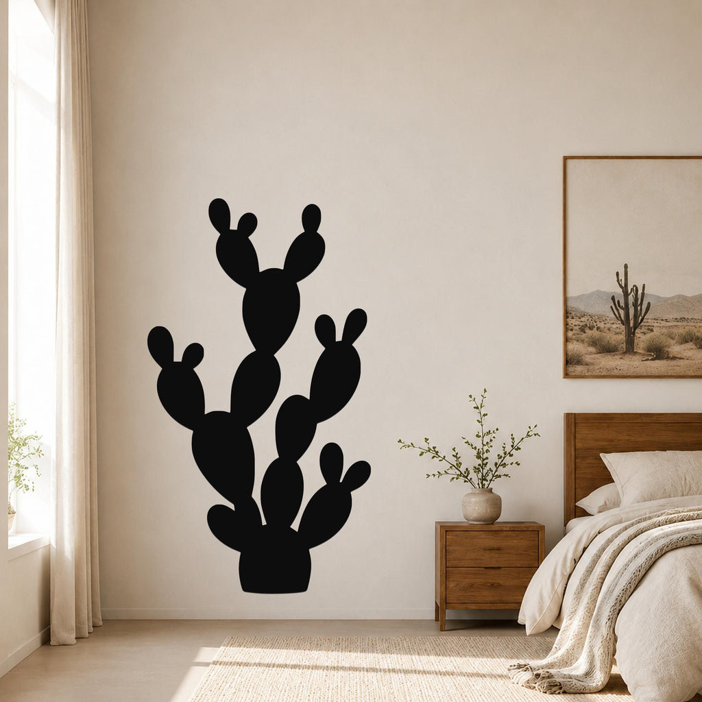 Black metal prickly pear cactus wall art silhouette mounted on a bedroom wall above a nightstand.