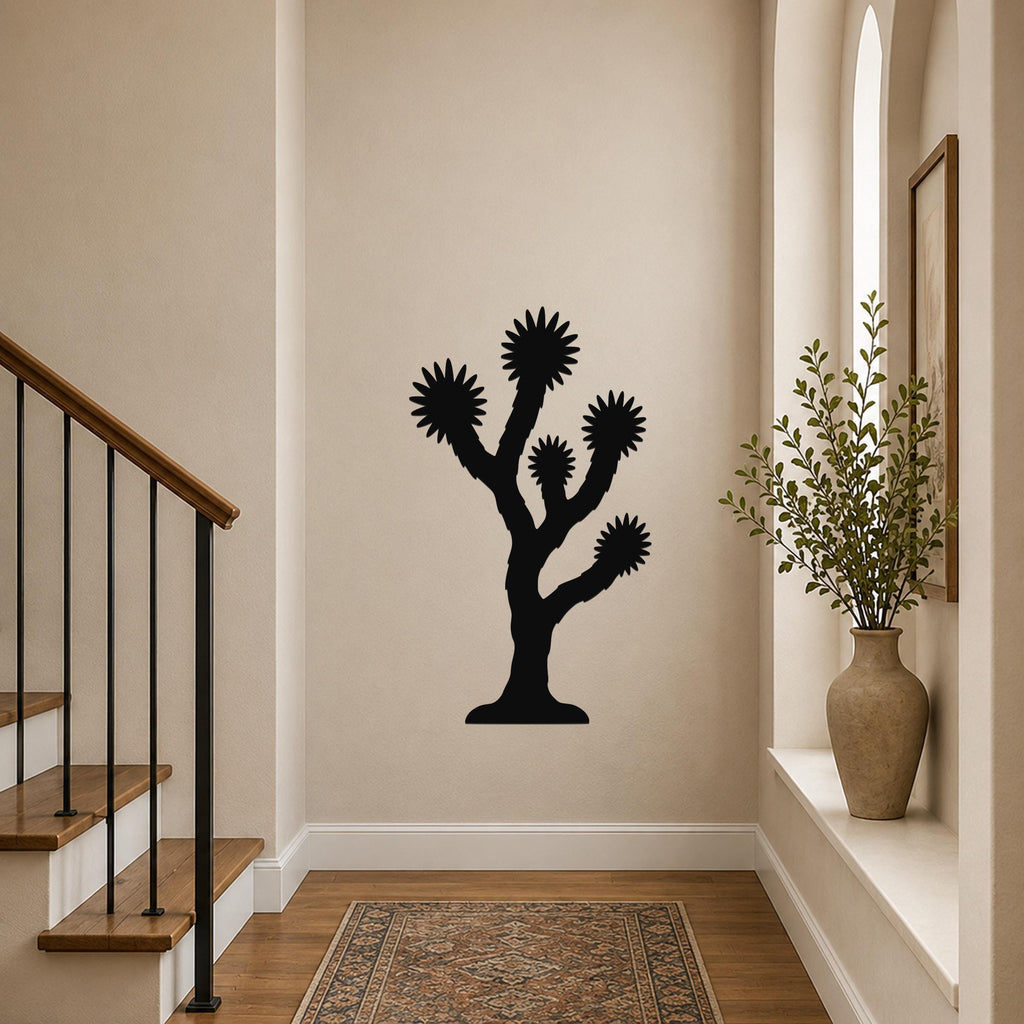 Black metal Joshua tree wall art with spiky branch cutouts, mounted on a hallway wall above a patterned rug near a staircase.