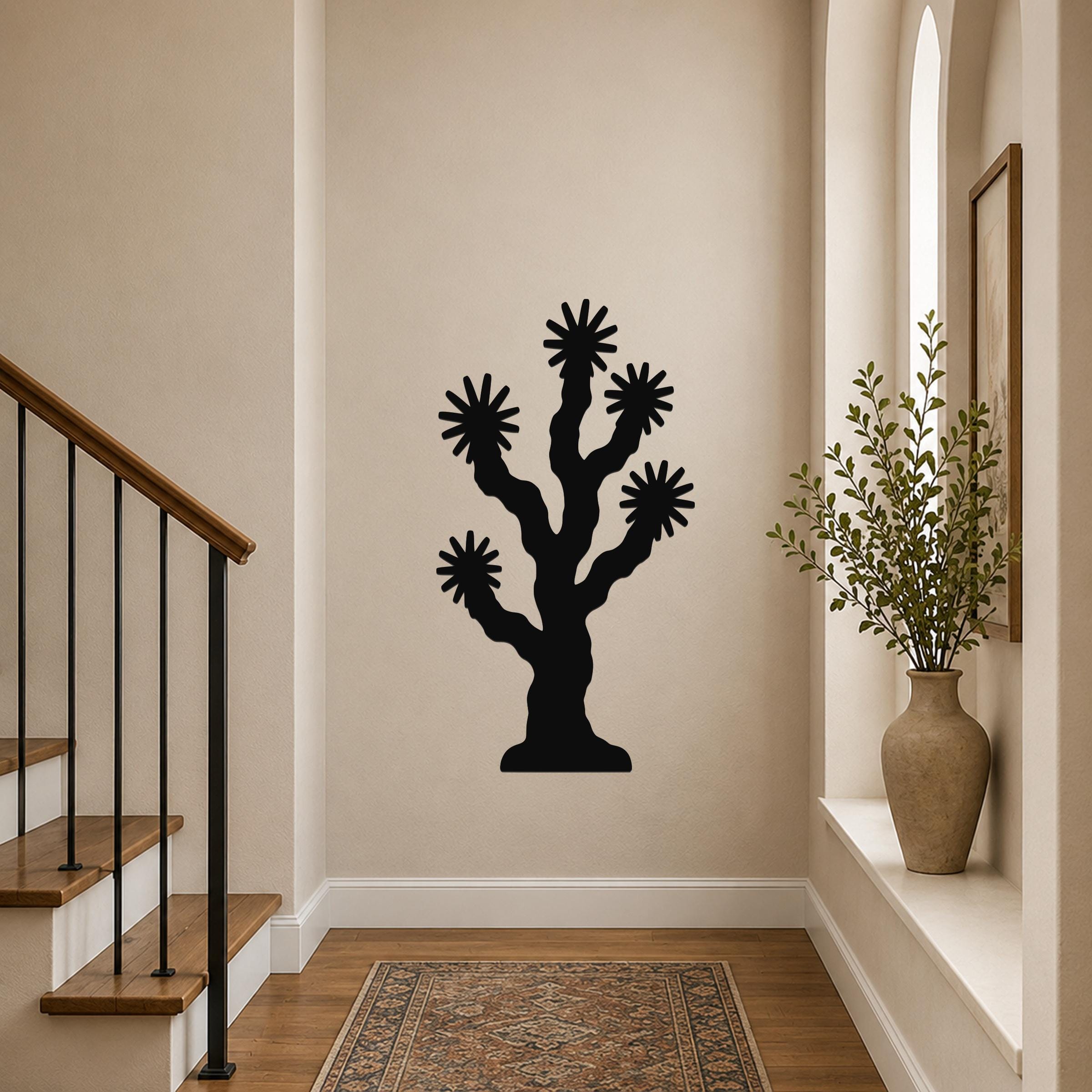 Black metal Joshua tree wall art with starburst cutouts, mounted on a hallway wall above a patterned rug near a staircase.