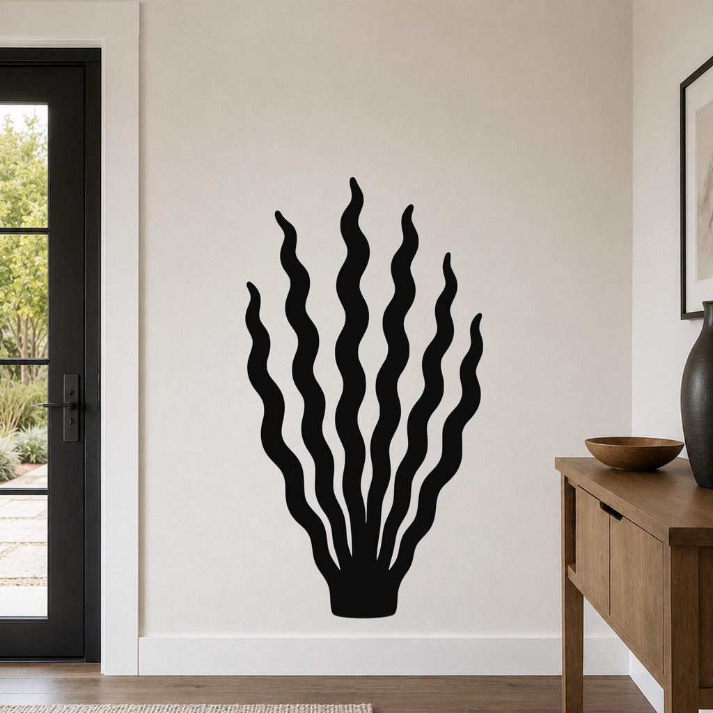 Black metal wall art in a kelp or seaweed silhouette design, mounted on a light-colored wall in a living room near a door and console table.