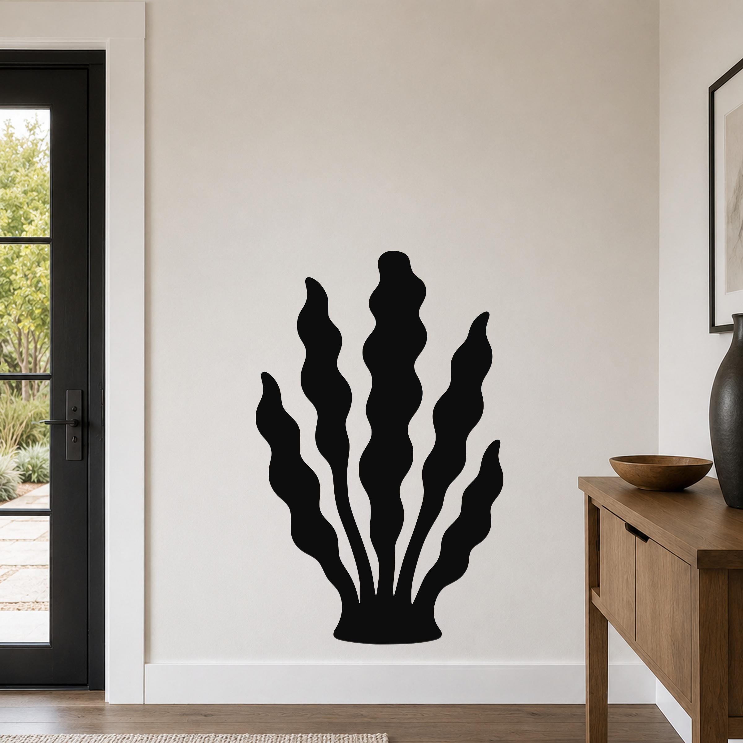 Black metal kelp wall art with wavy leaf cutouts, mounted on a living room wall above a wooden console table.