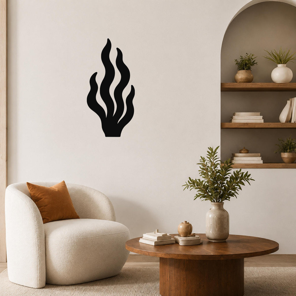 Black metal kelp wall art with flowing leaf cutouts, mounted on a living room wall above a white armchair.