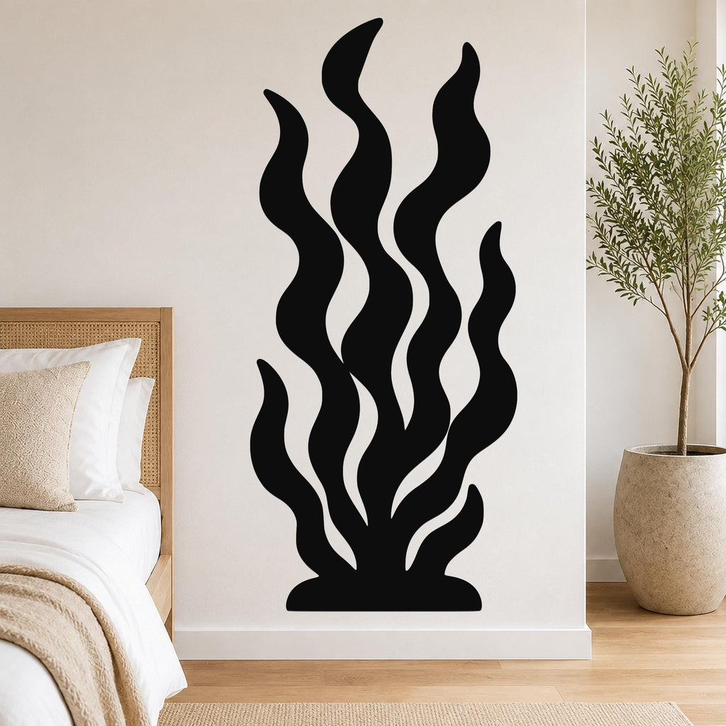 Black metal wall art in a kelp or seaweed silhouette design with flowing wavy lines, mounted on a bedroom wall above a bed.