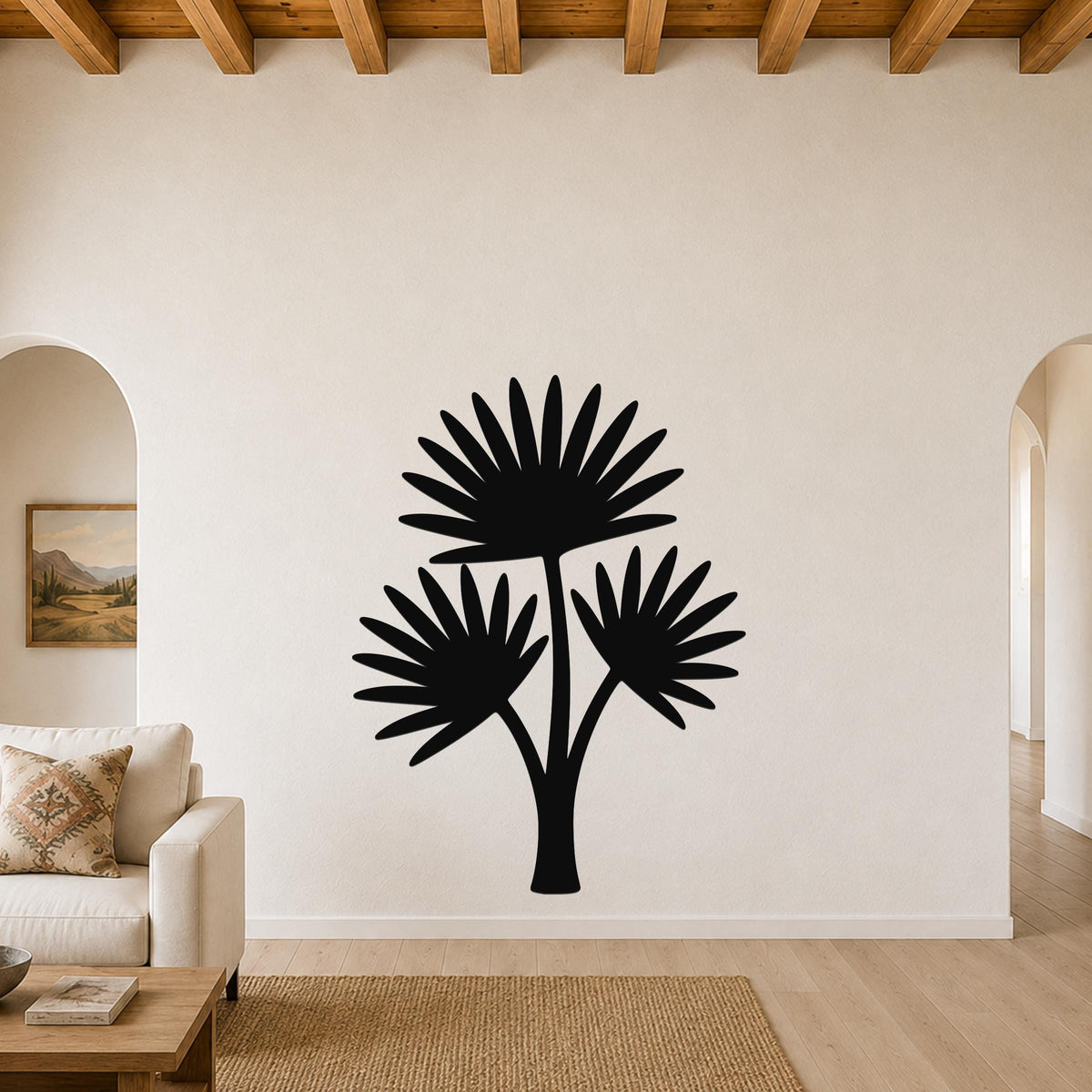 Black metal cutout wall art of a fan palm tree with three fronds, mounted on a living room wall above a sofa.