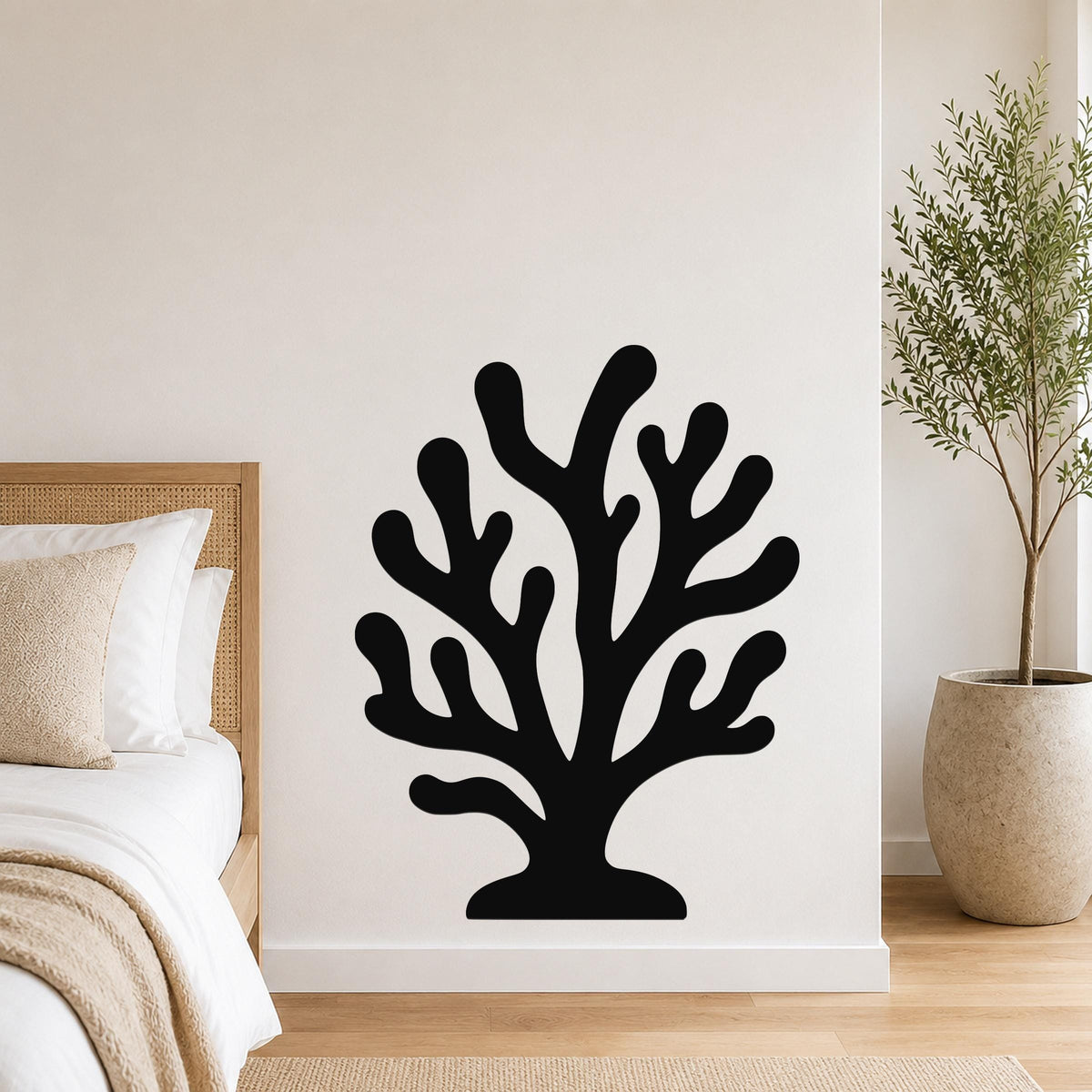 Black metal coral wall art with branching cutouts, mounted on a white bedroom wall above a bed.