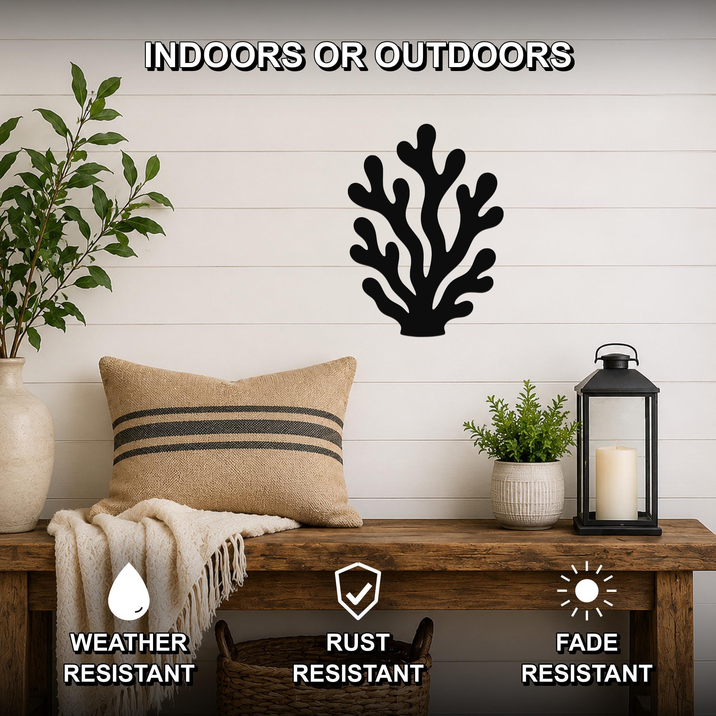 Black metal coral wall art with branching cutouts, mounted on a white shiplap wall above a wooden bench in a living room.