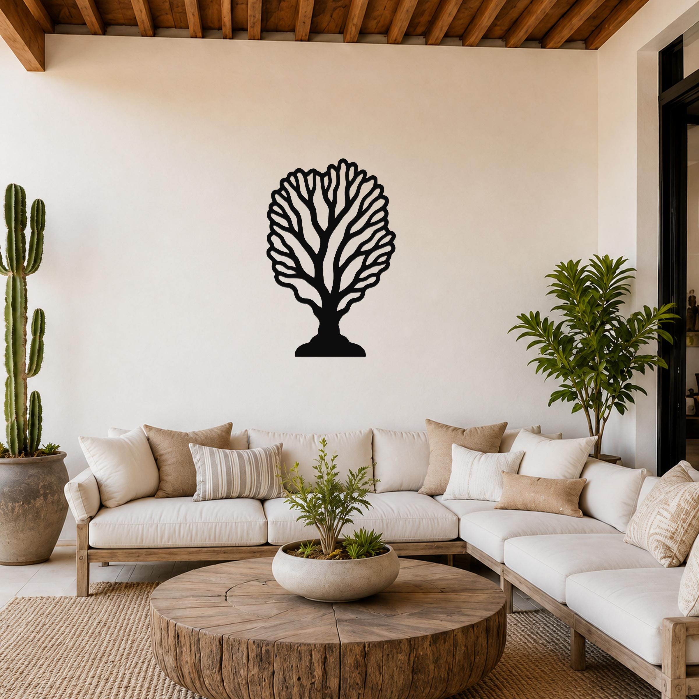 Black metal fan coral wall art with intricate branch cutouts, mounted on a living room wall above a white sofa.