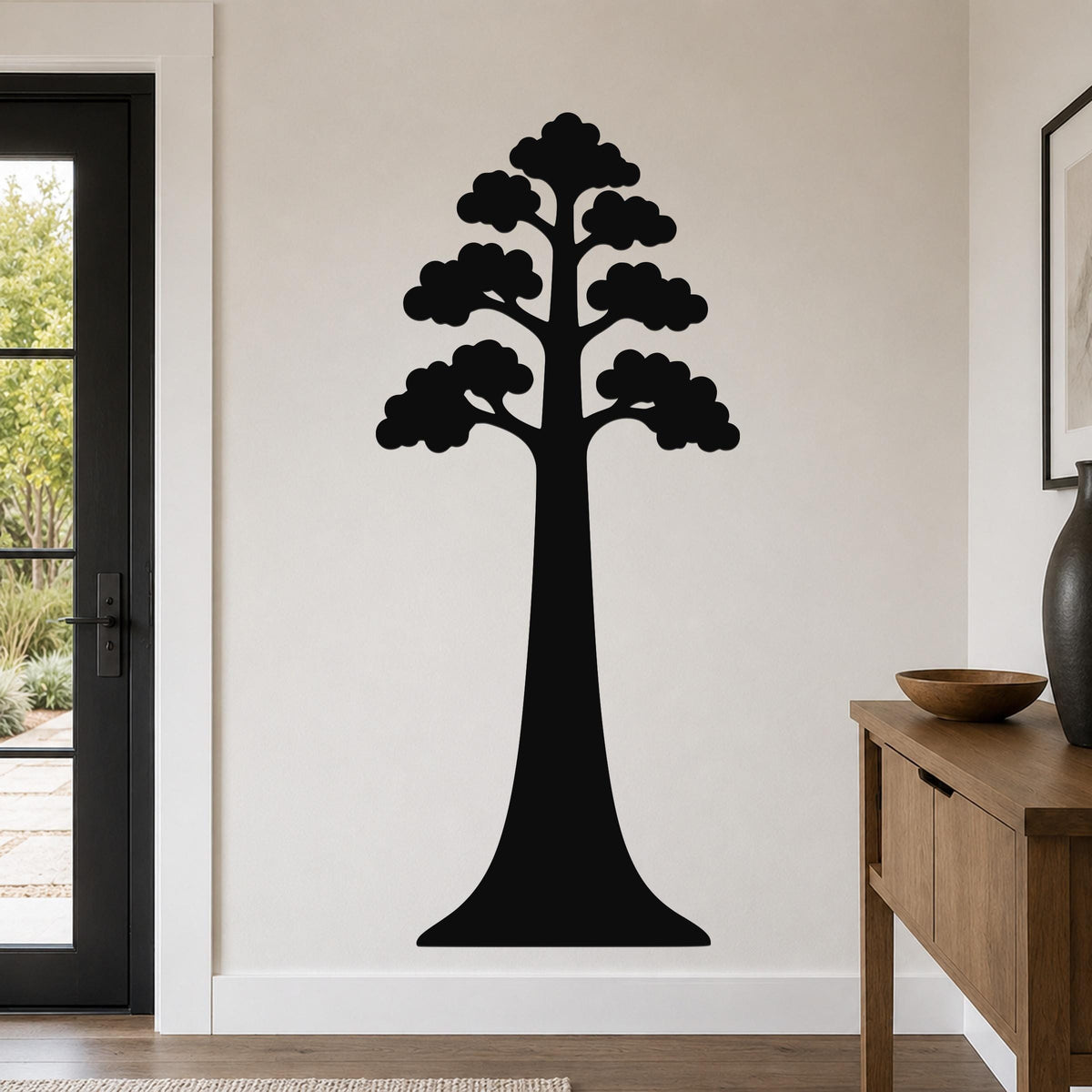 Black metal sequoia tree wall art with layered branch cutouts, mounted on a living room wall above a wooden console table.