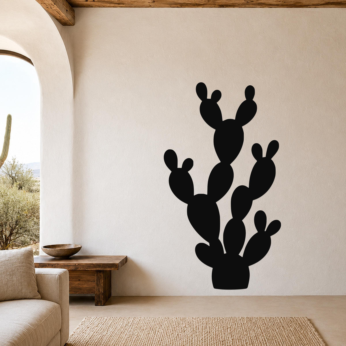 Black metal prickly pear cactus wall art with multiple paddle-shaped segments, mounted on a beige living room wall above a wooden bench.