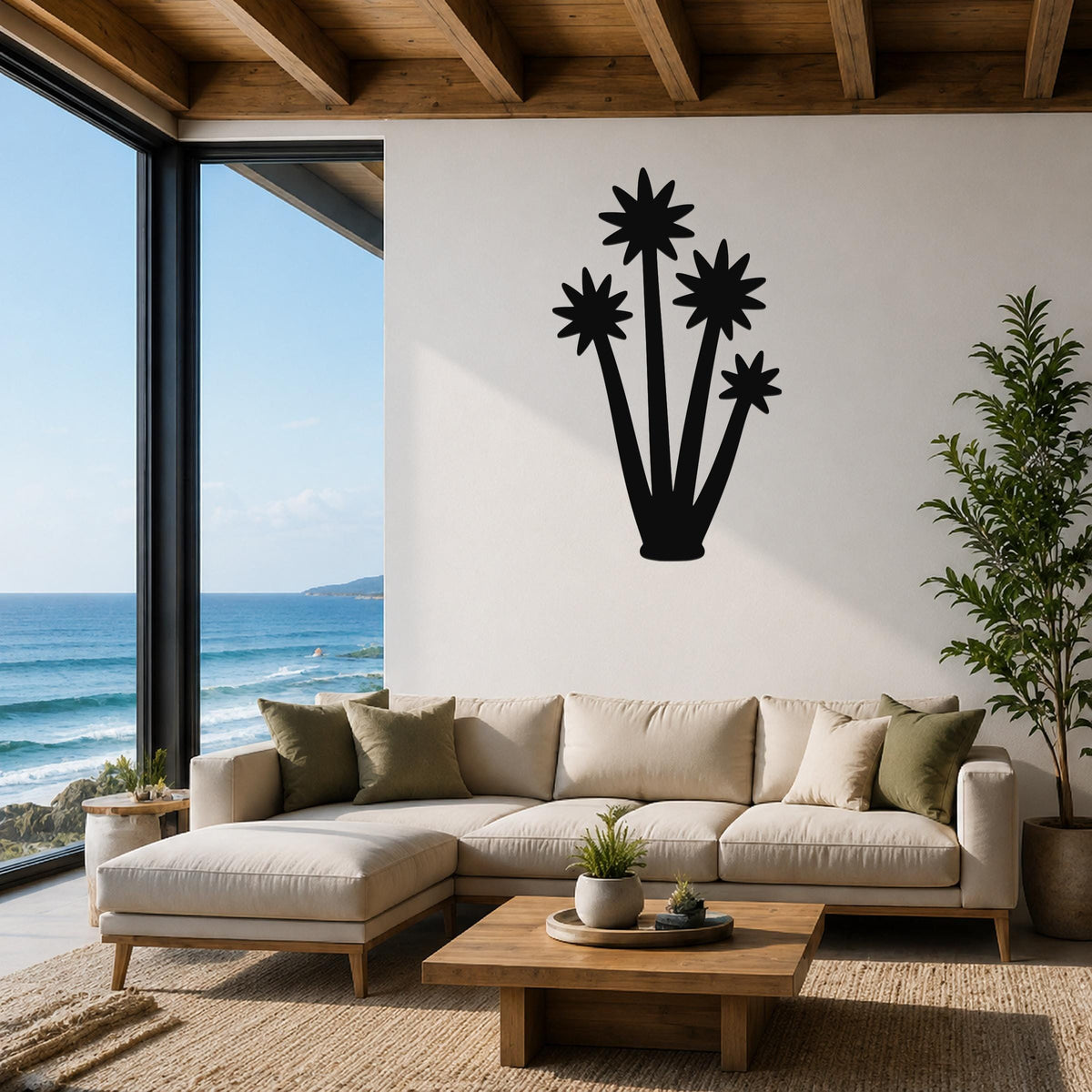 Black metal wall art silhouette of a tall yucca plant with star-shaped flower cutouts, mounted on a white wall above a beige sofa in a living room with ocean views.