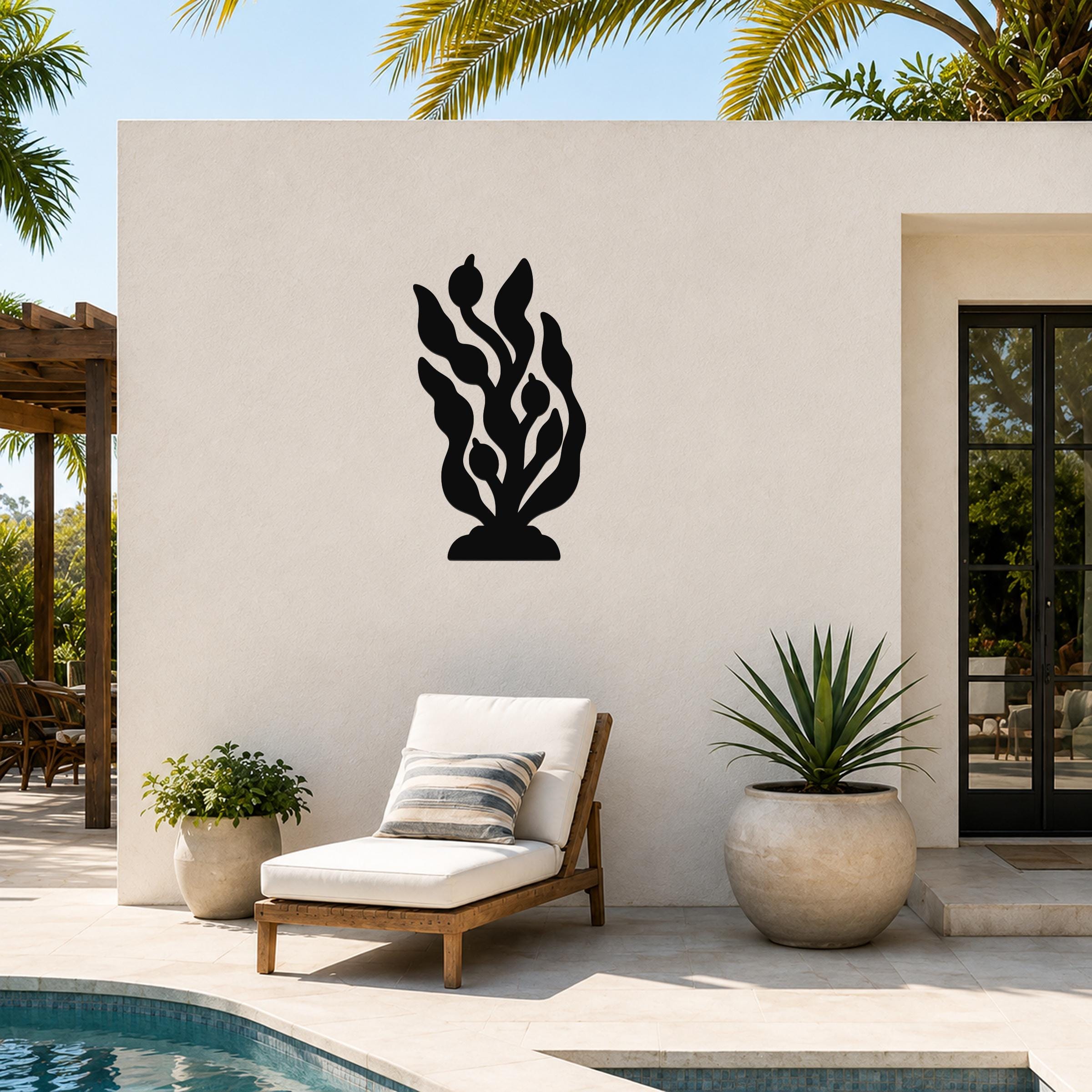 Black metal wall art in a kelp and seaweed silhouette design, mounted on an outdoor patio wall above a lounge chair.