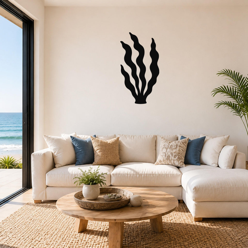 Black metal kelp wall art with wavy blade cutouts, mounted above a white sectional sofa in a coastal living room.