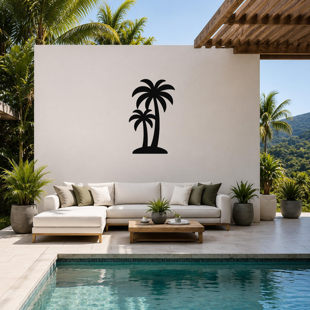 Black metal twin palm trees wall art silhouette mounted on a white outdoor wall above a white sectional sofa in a patio living area.
