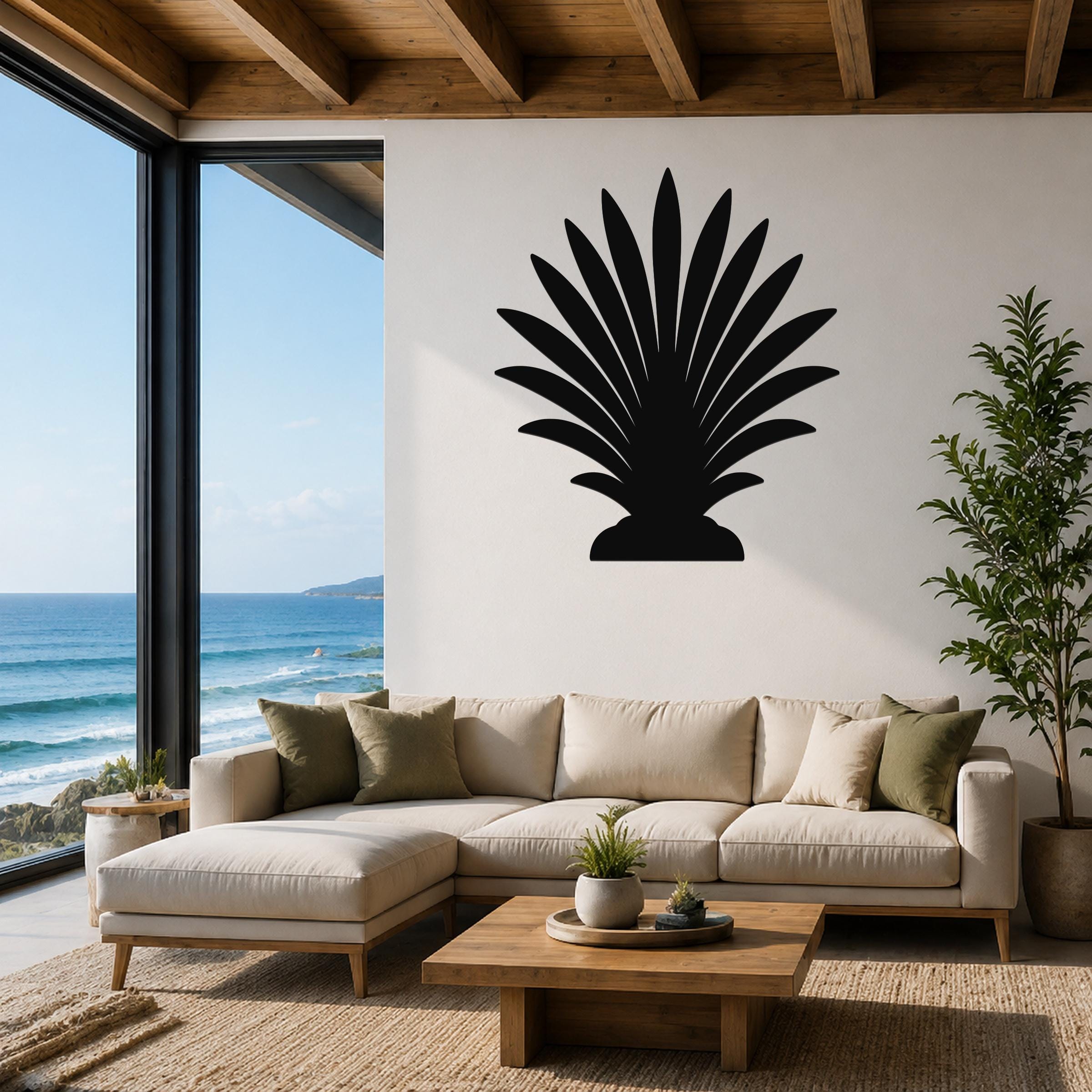 Black metal palm tree wall art with fan-shaped fronds, mounted on a white wall above a beige sectional sofa in a living room with ocean views.