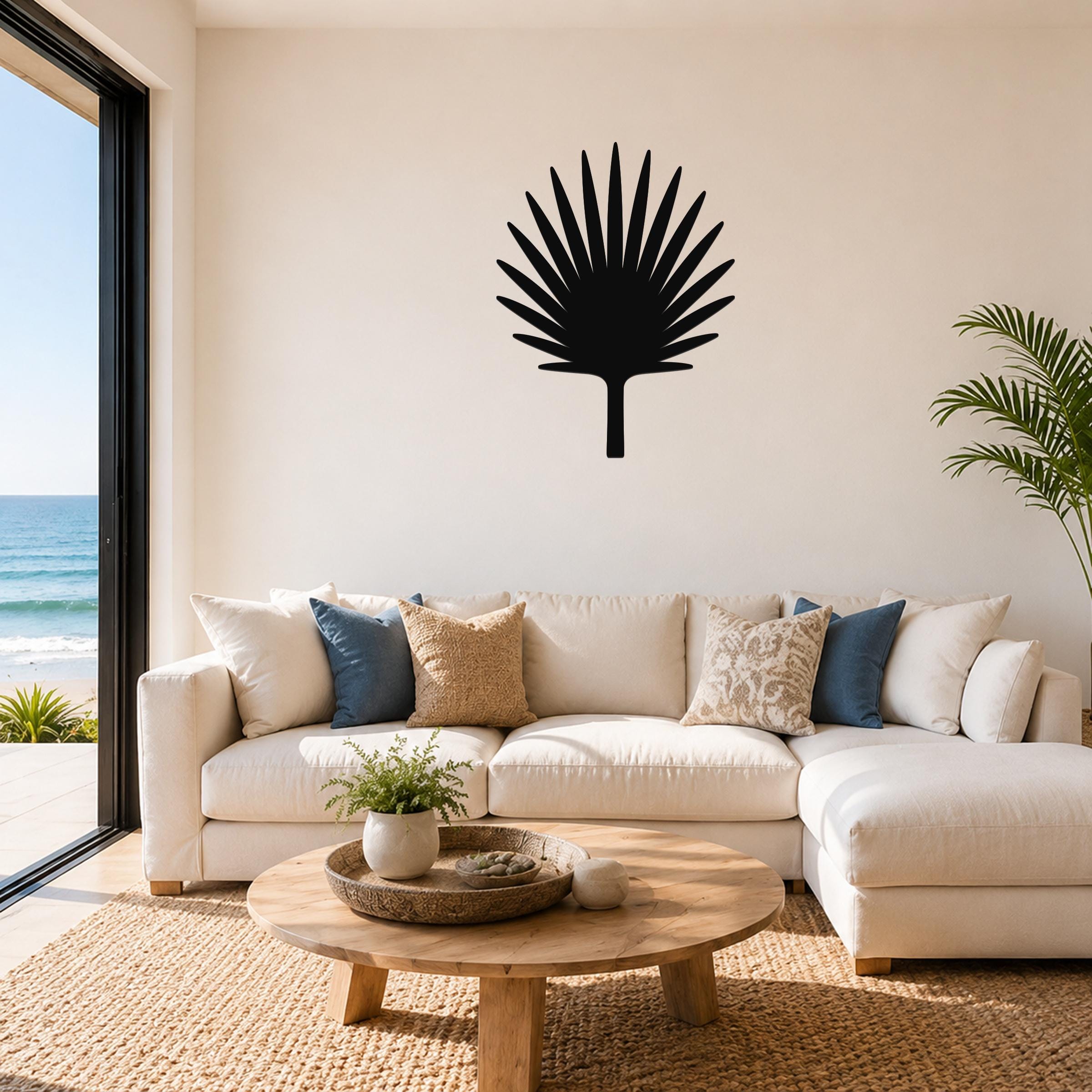 Black metal fan palm tree wall art with radiating leaf cutouts, mounted on a living room wall above a white sectional sofa.